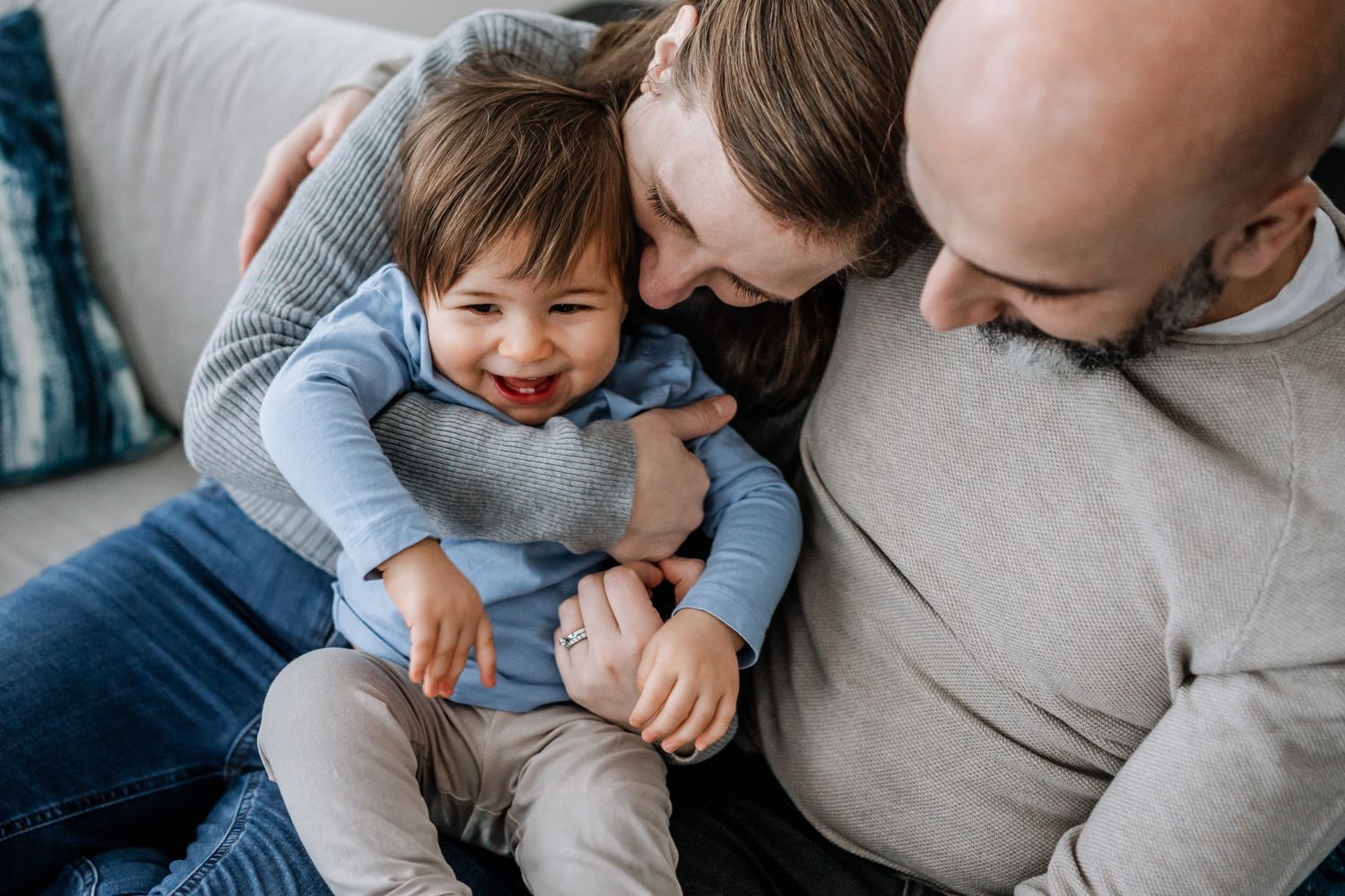 Det lilla barnet busar med sina föräldrar under familjefotograferingen i hemmet.