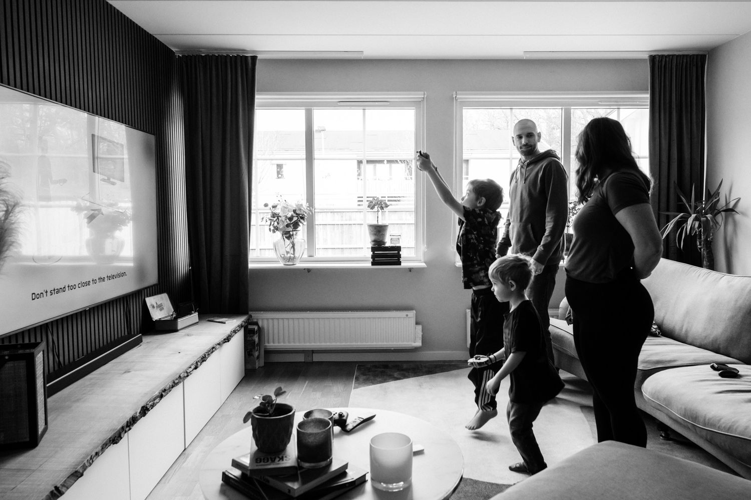 En familj i siluett i ett vardagsrum när de står framför tv:n.