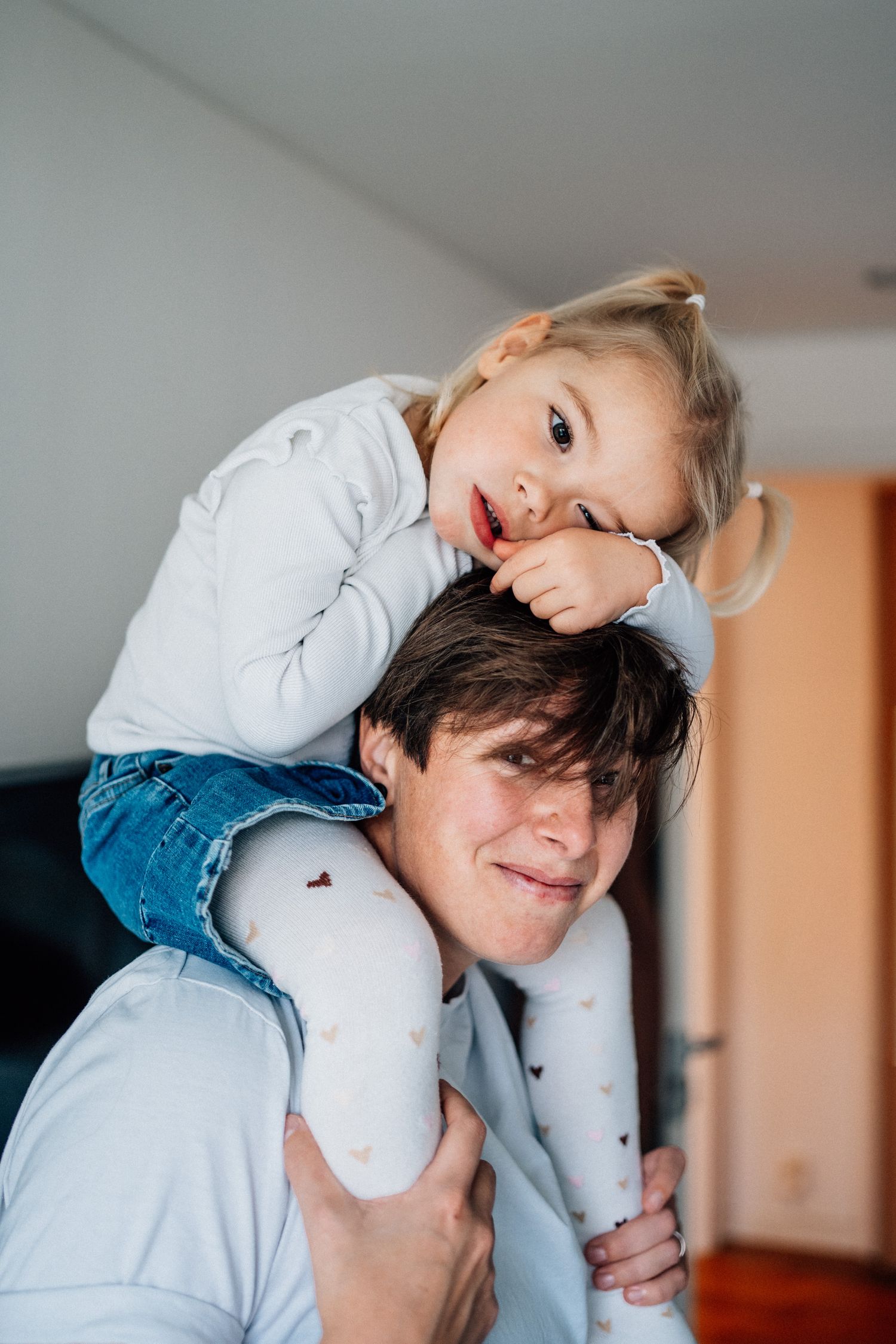 Barnet sitter på sin mammas axlar och lutar sig mot mammans huvud.