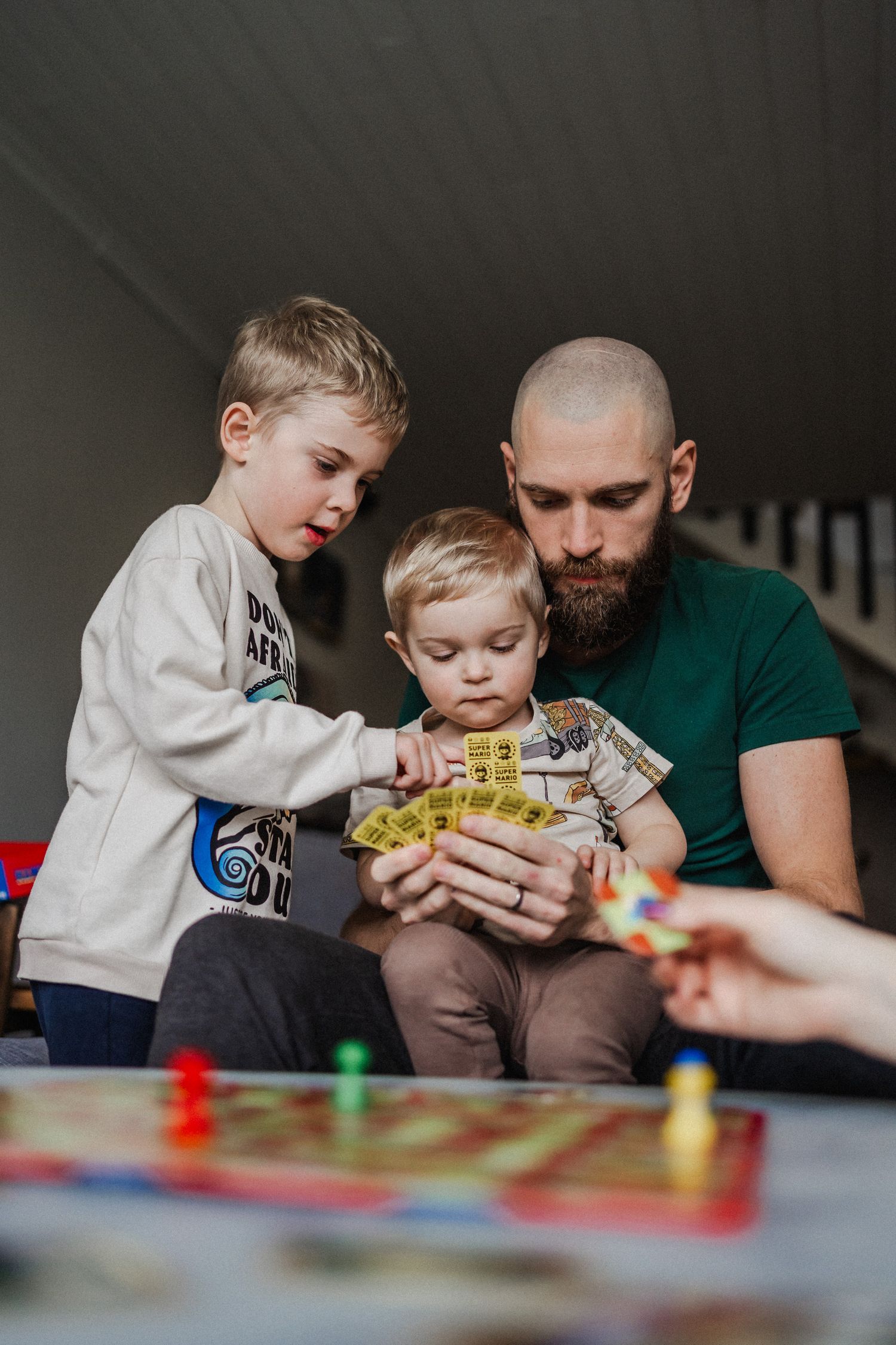 De två pojkarna spelar ett sällskapsspel med sin pappa.