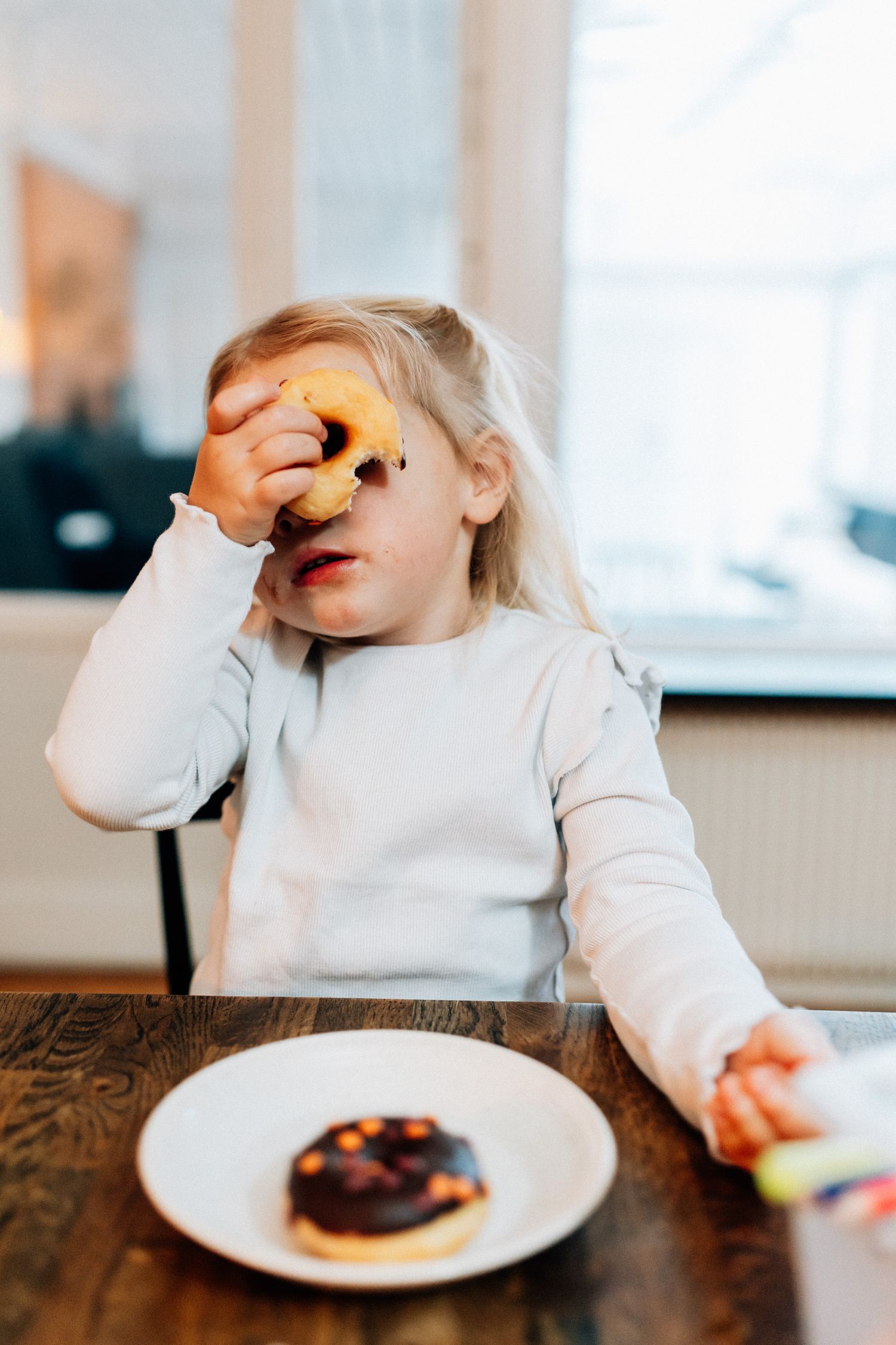 En liten flicka tittar igenom hålet på en munk.