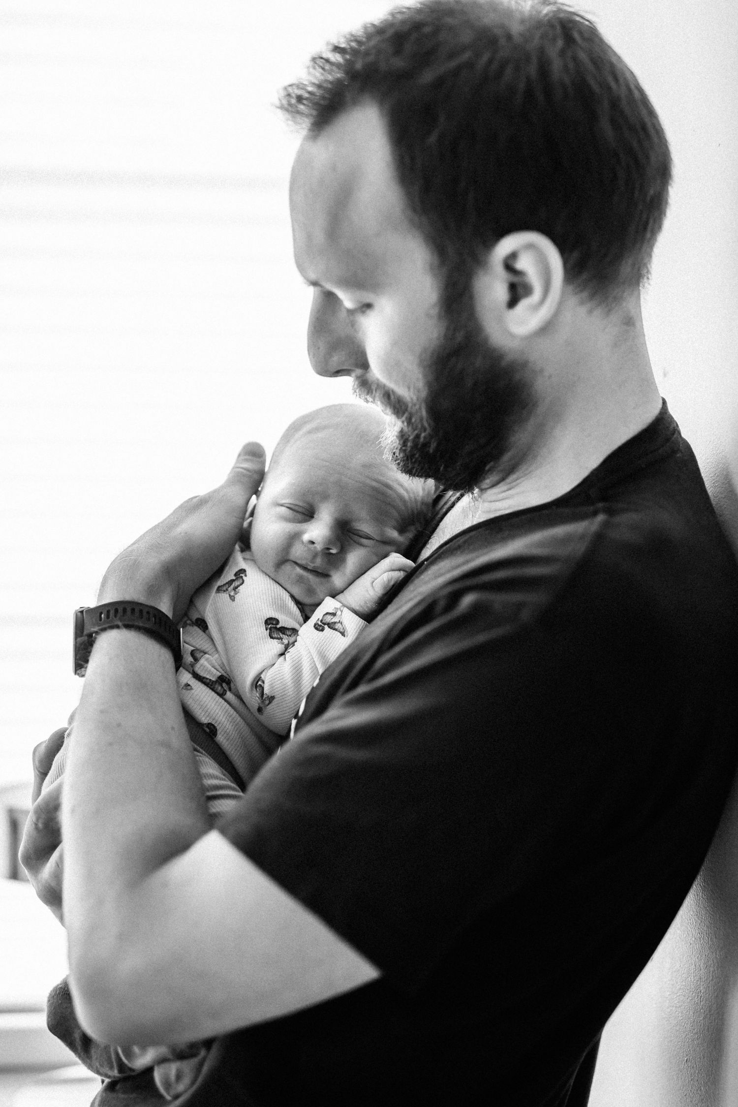 Pappan håller i sitt nyfödda barn under familjefotograferingen.