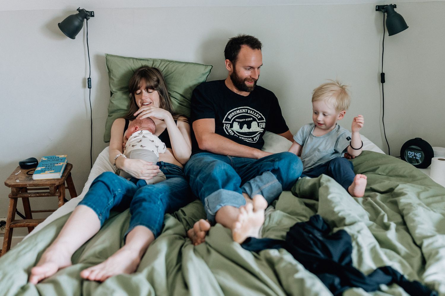 En familj med två små barn sitter i en säng.