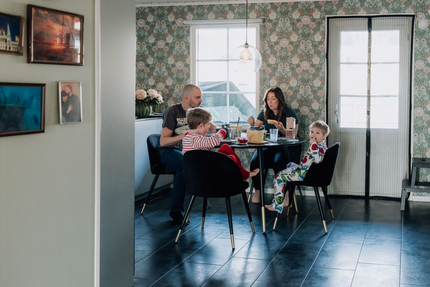 En familj sitter vid ett bord och äter frukost under den dokumentära familjefotograferingen.