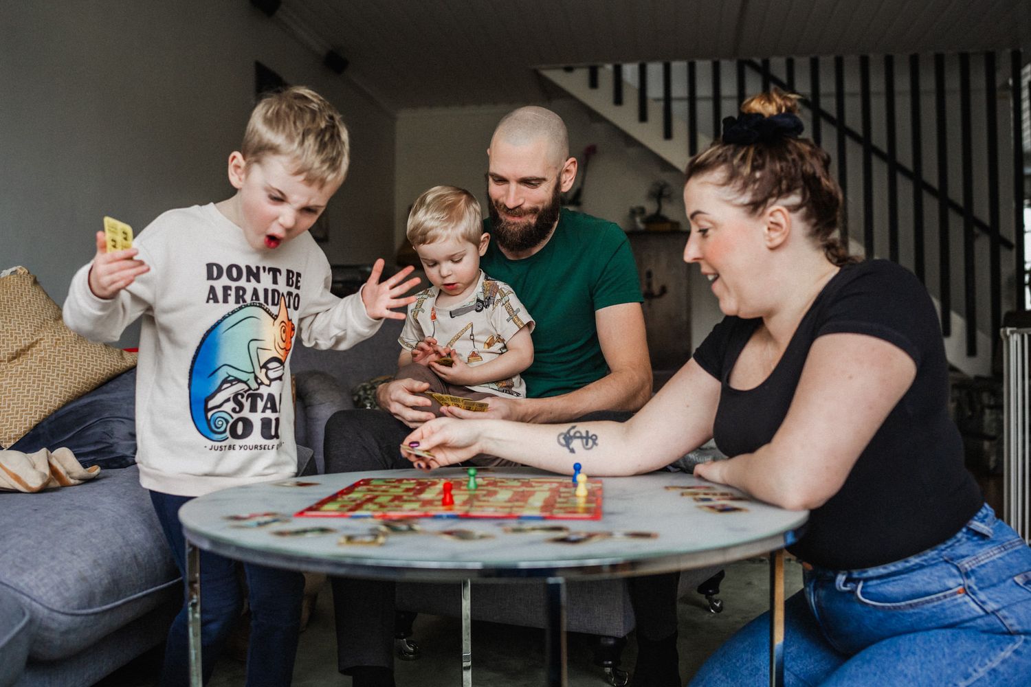 Familjen sitter vid ett bord och spelar ett sällskapsspel.