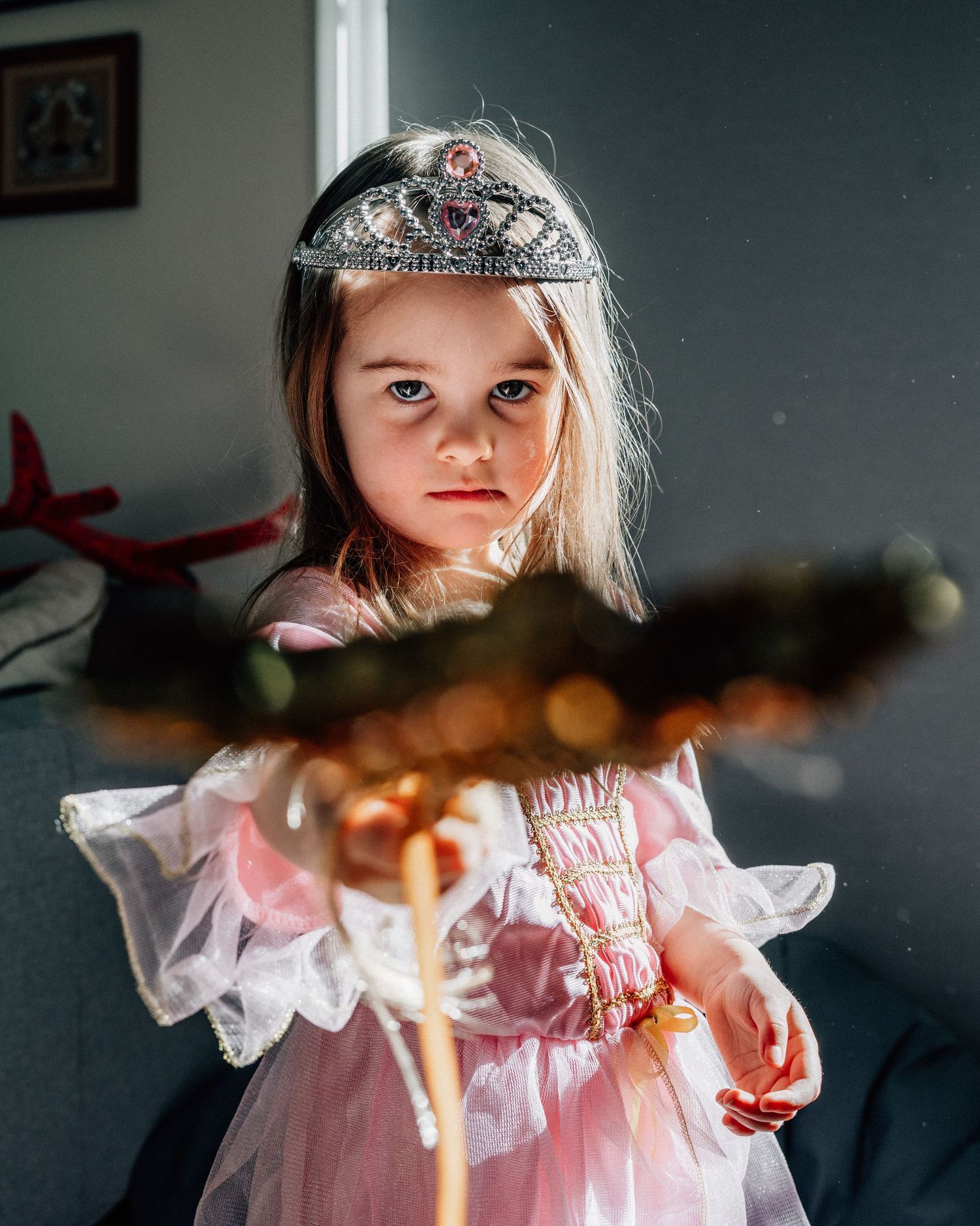Flickan är utklädd till prinsessa och pekar med sin stav mot kameran.