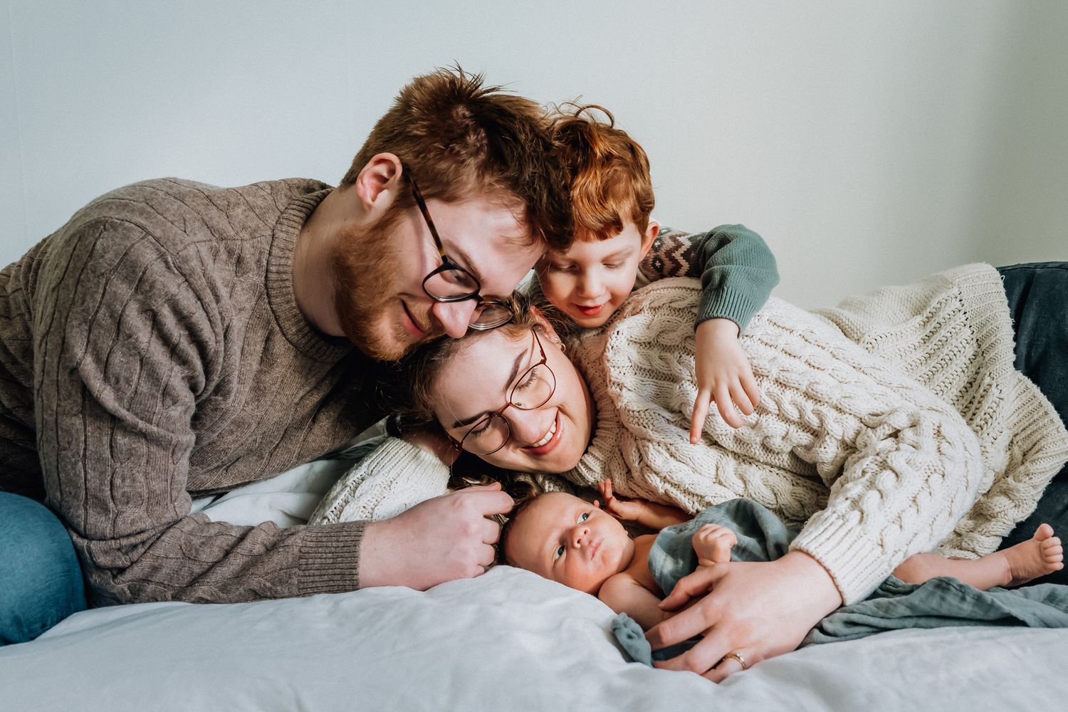 Familjen ligger bredvid och tittar på sin nyfödda bebis.