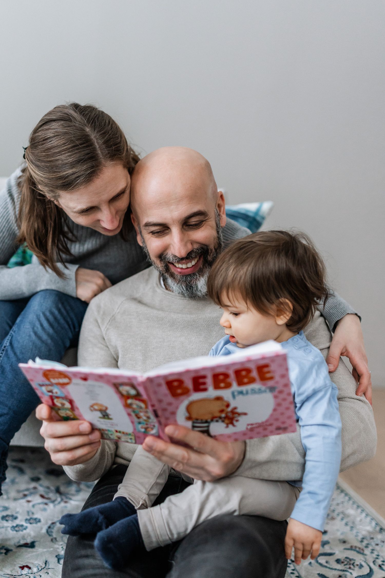 En familj med ett litet barn sitter och läser en bok.