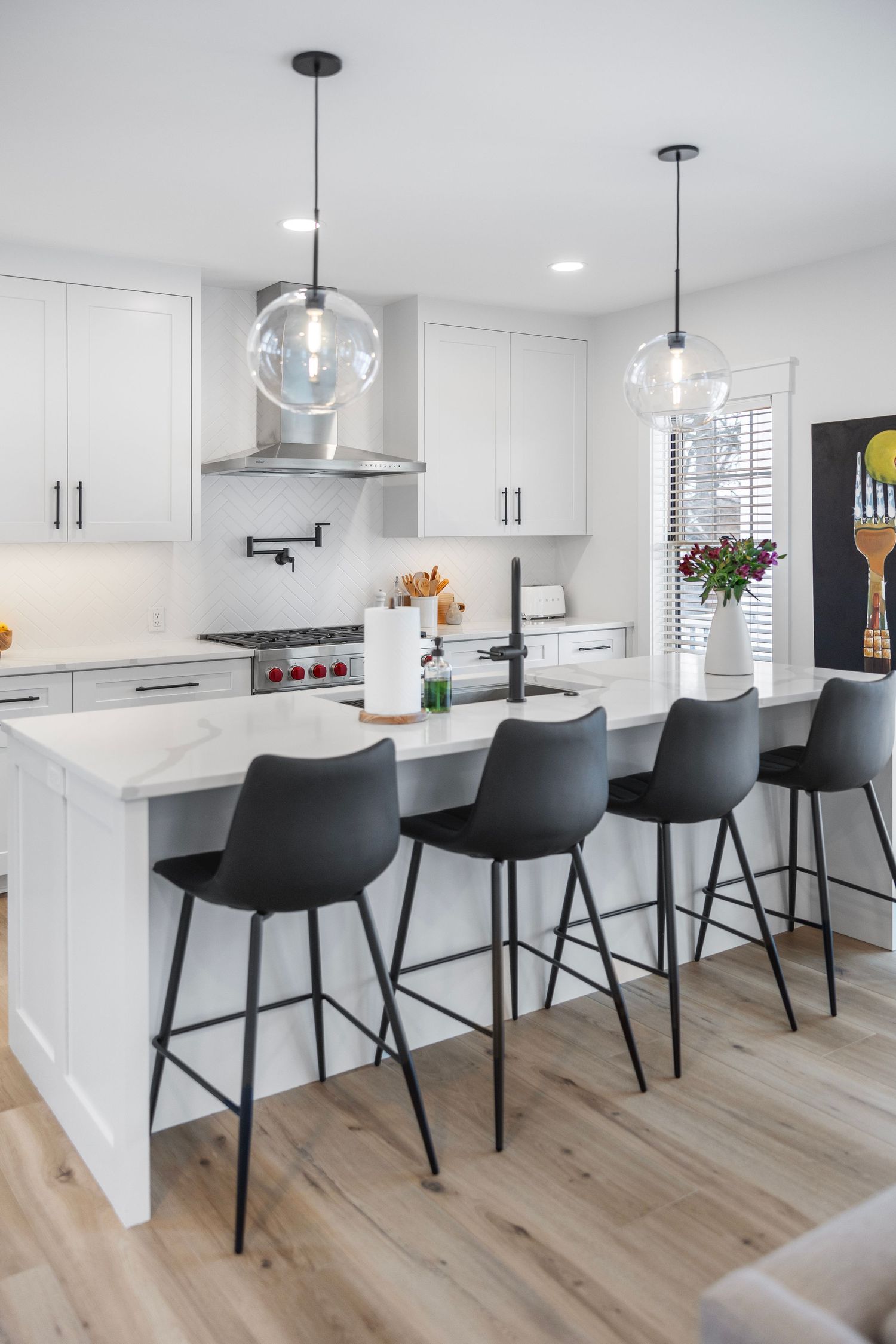 Contemporary kitchen featuring glass globe pendant lights, white cabinets and four modern black barstools.