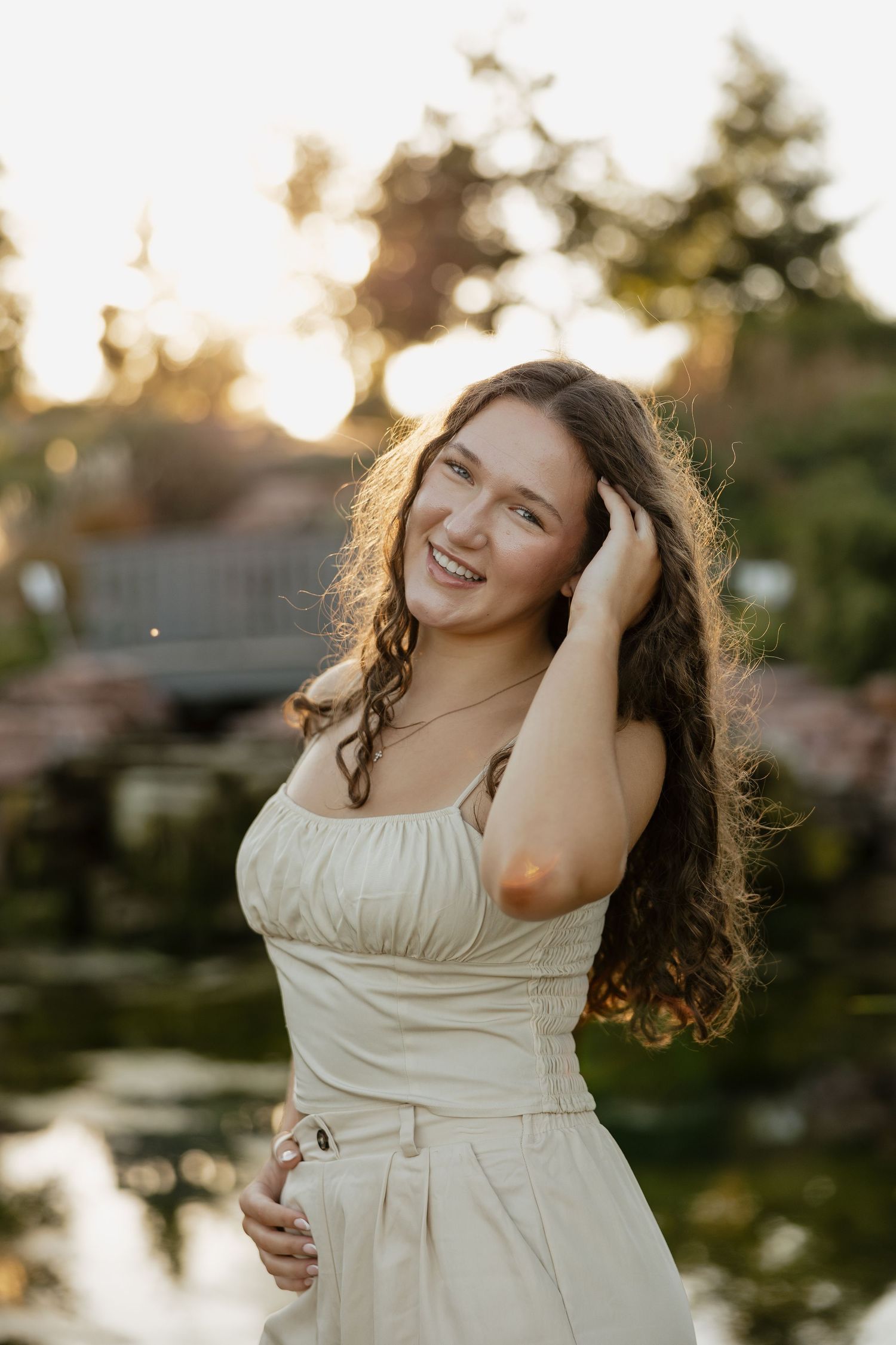 Woman in white dress smiling during golden hour photoshoot.