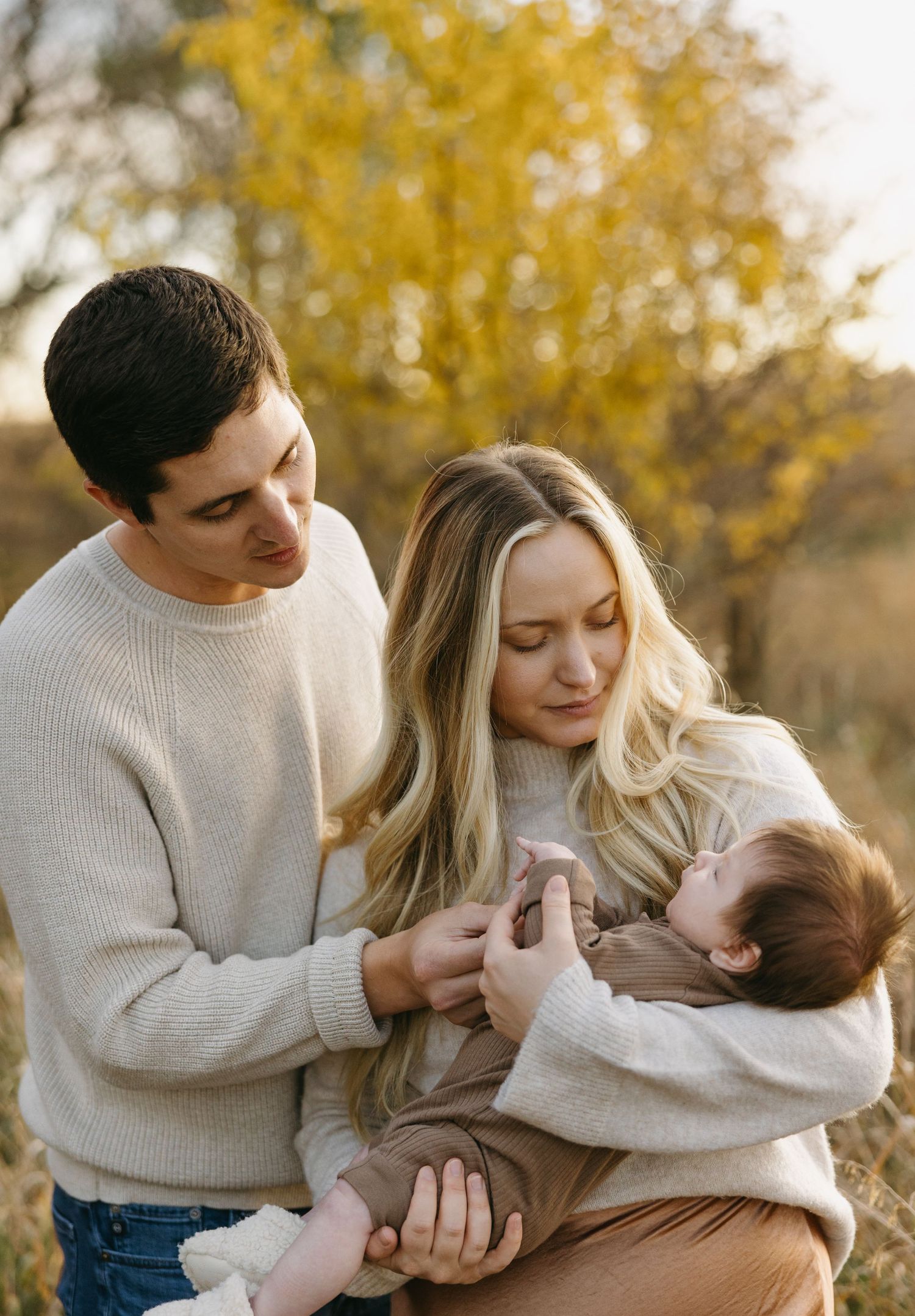 Tender family moment outdoors with autumn colors in background.
