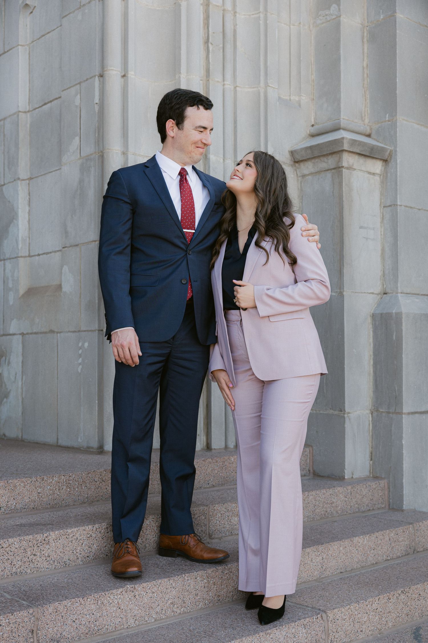A couple in formal attire pose together against stone pillars in four similar romantic shots.