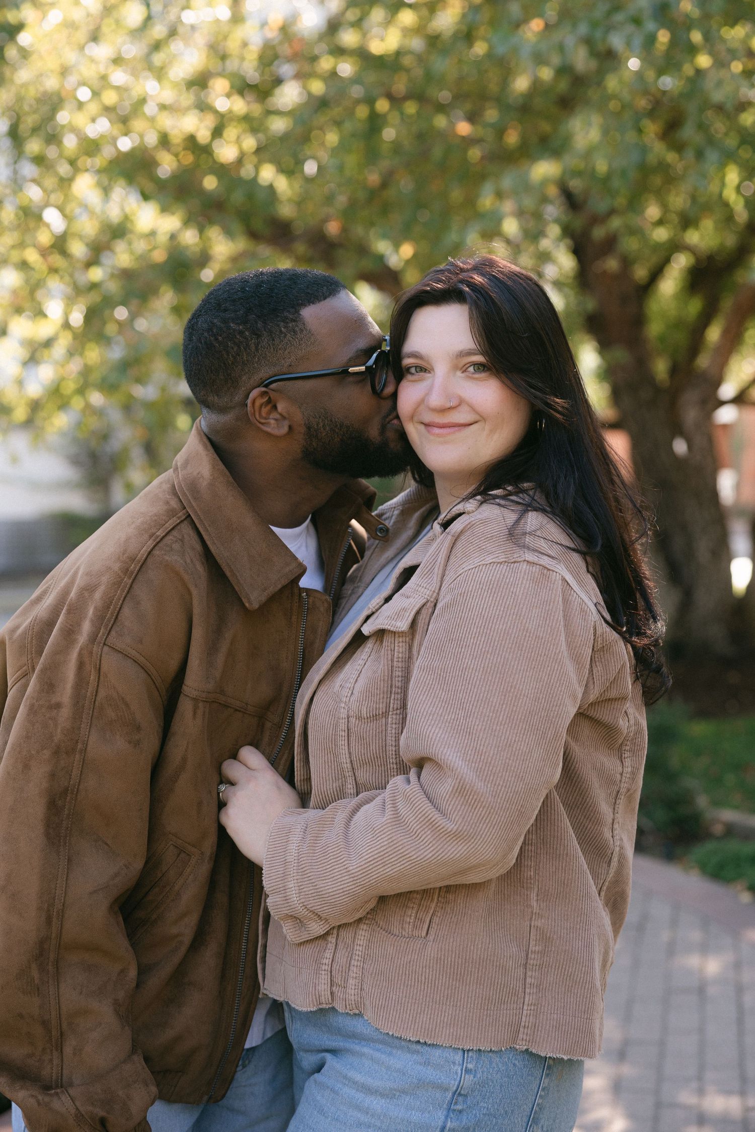 A romantic moment shared between a couple in casual attire against a blurred natural background.