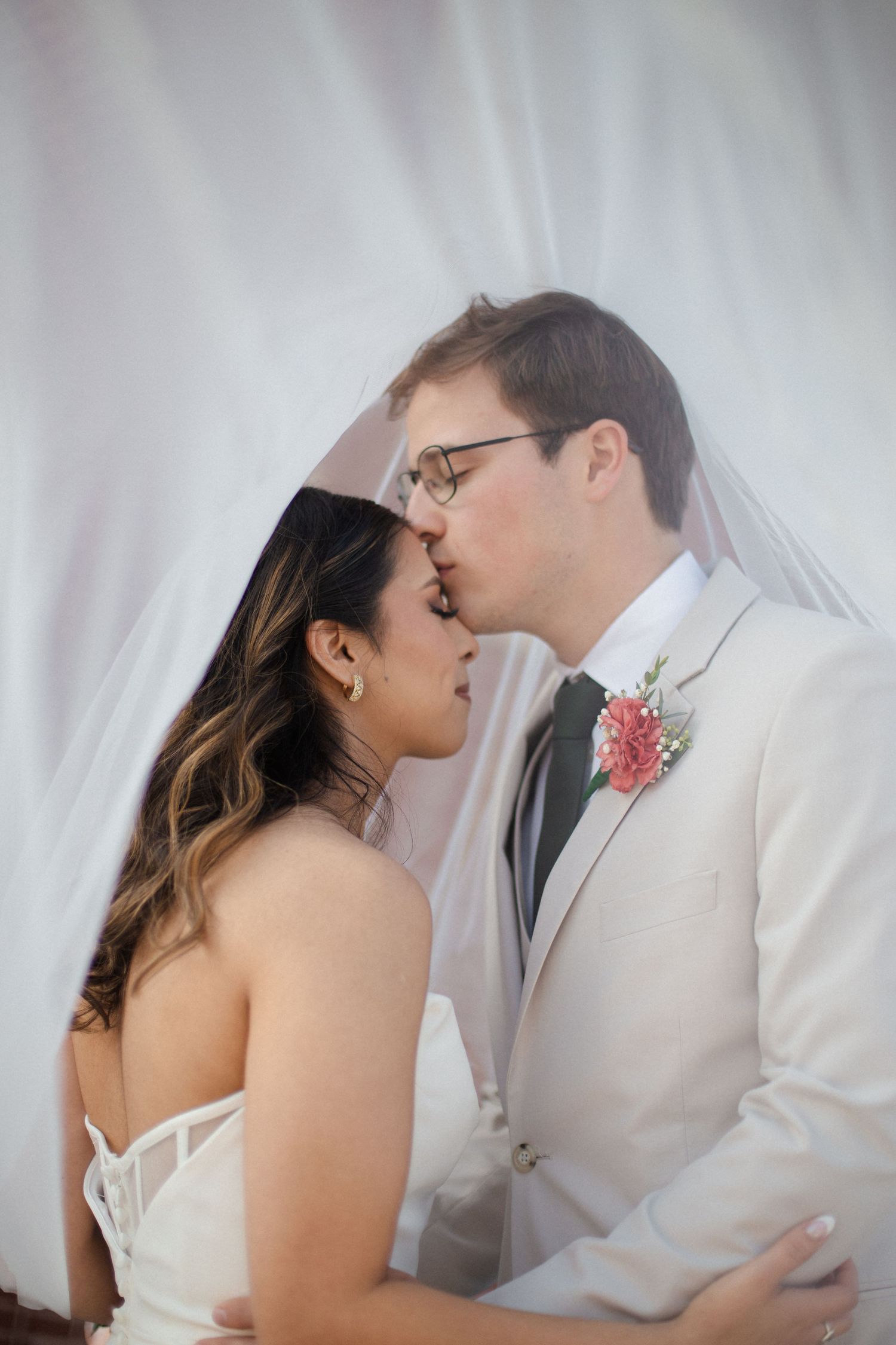 A romantic wedding couple shares an intimate kiss in a series of four soft-focused photos with white backgrounds.