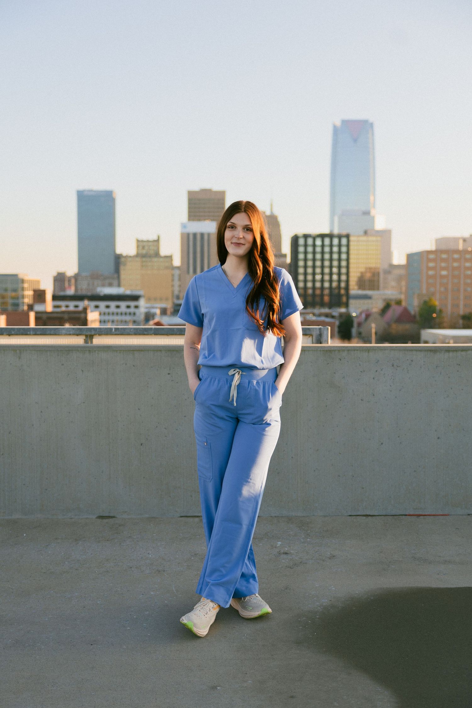 Figure in blue denim jumps gracefully against an urban skyline backdrop at dusk.