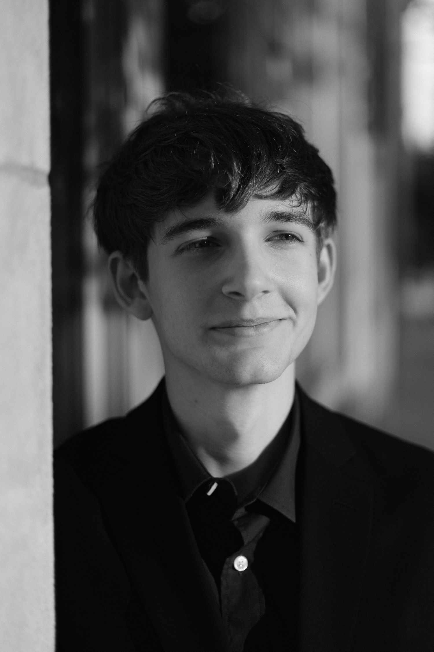 Black and white portrait showing a gentle smile against a blurred background.