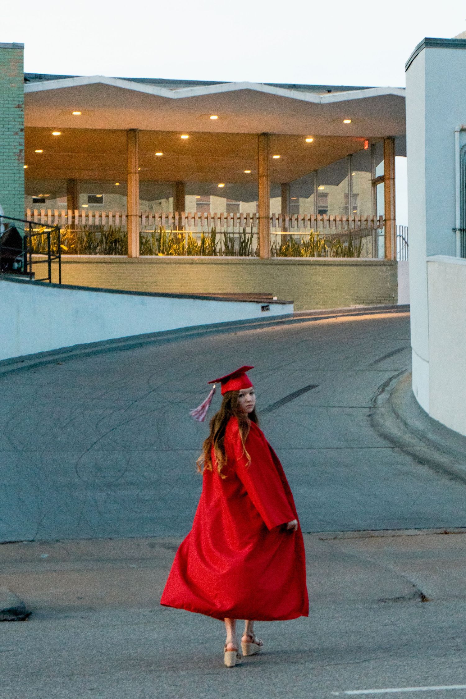 Movement captured in series showing a figure in flowing red graduation attire against a stark parking lot background.