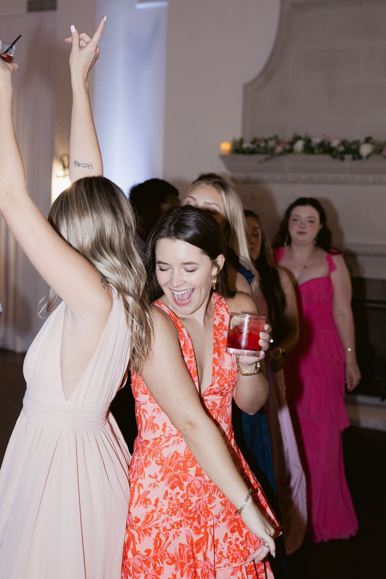 Wedding guests dance and celebrate with drinks at the reception party.