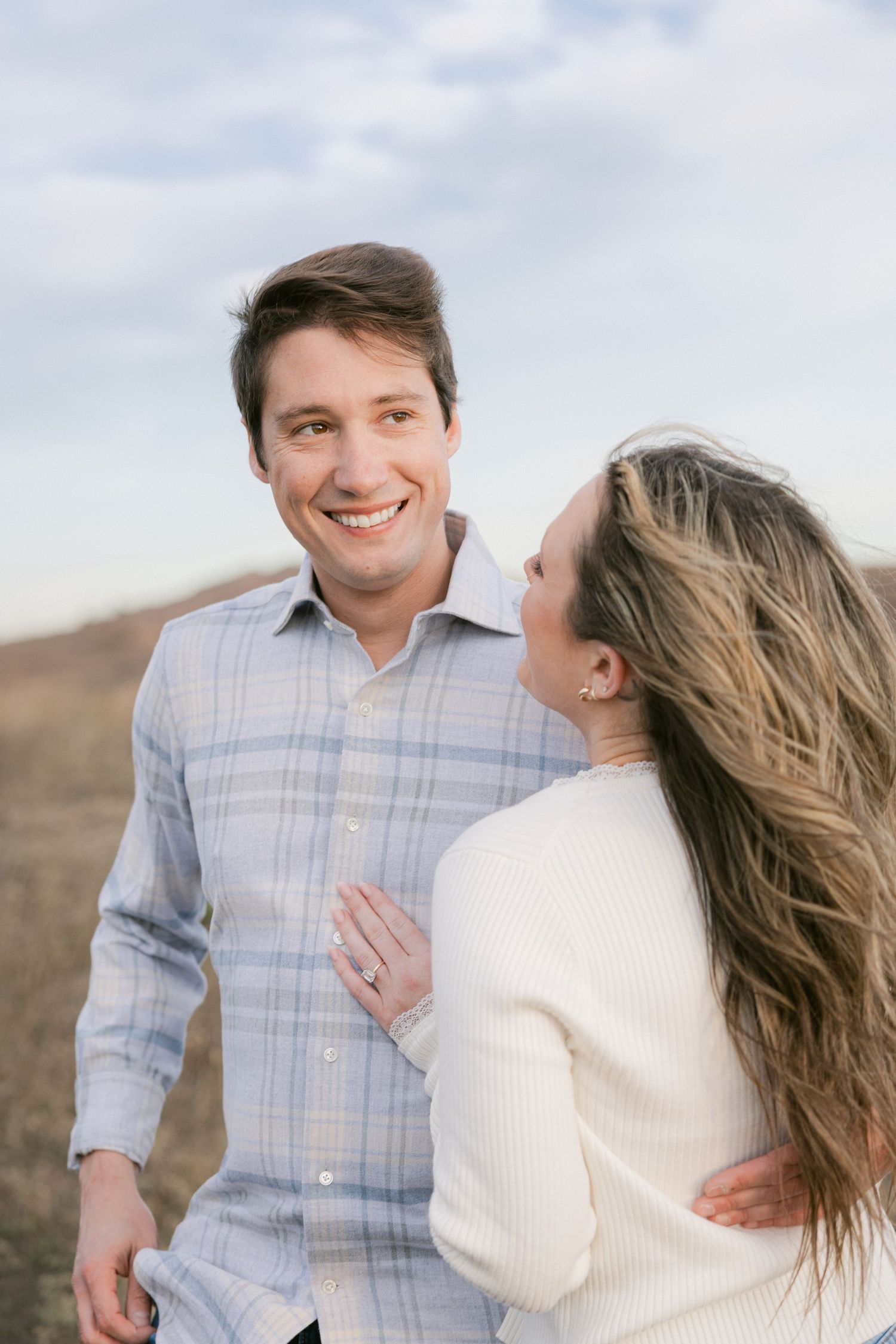 A couple shares joyful moments together in a field on an overcast day.