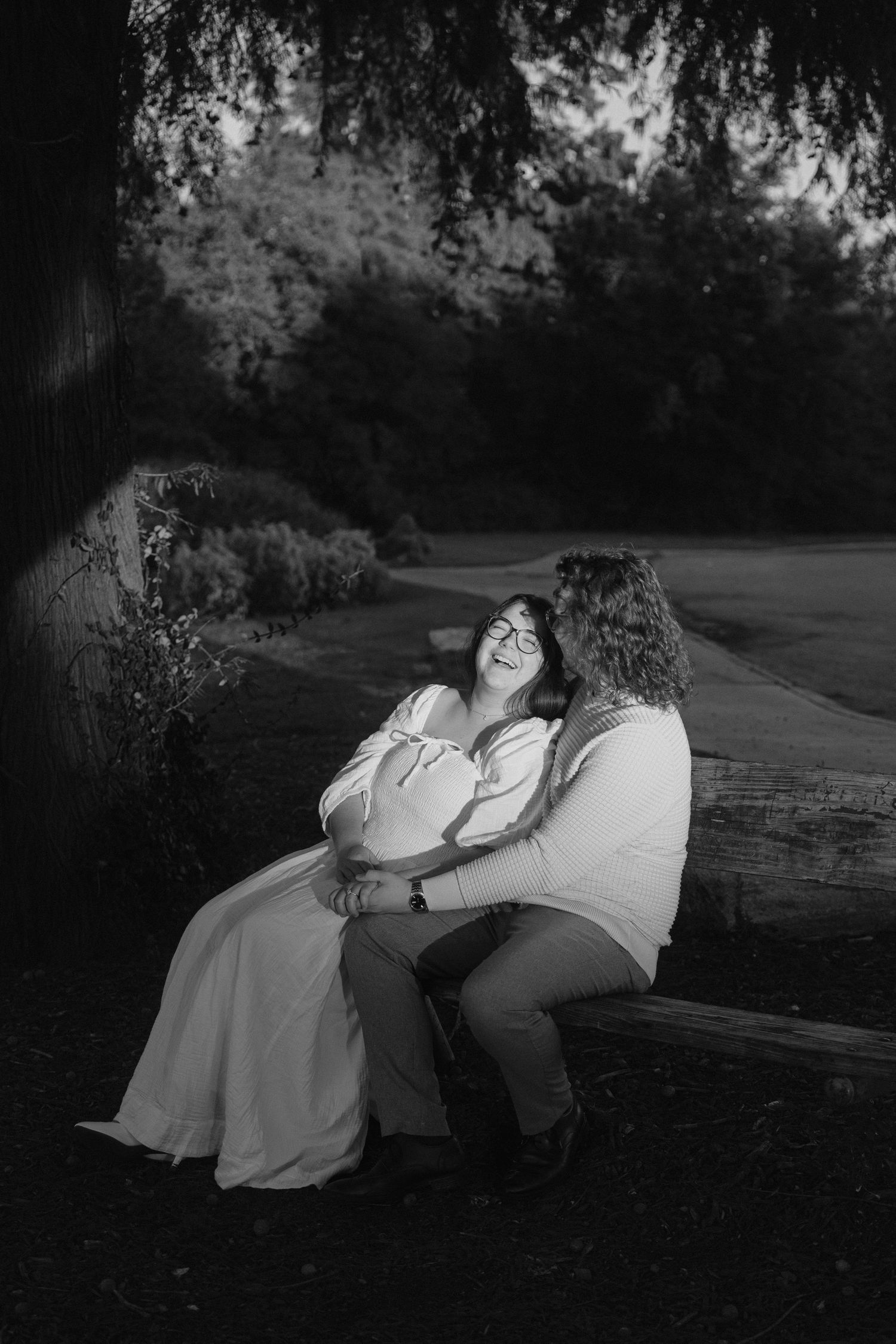 A romantic black and white photo series showing a couple sitting on a bench in a park at dusk.
