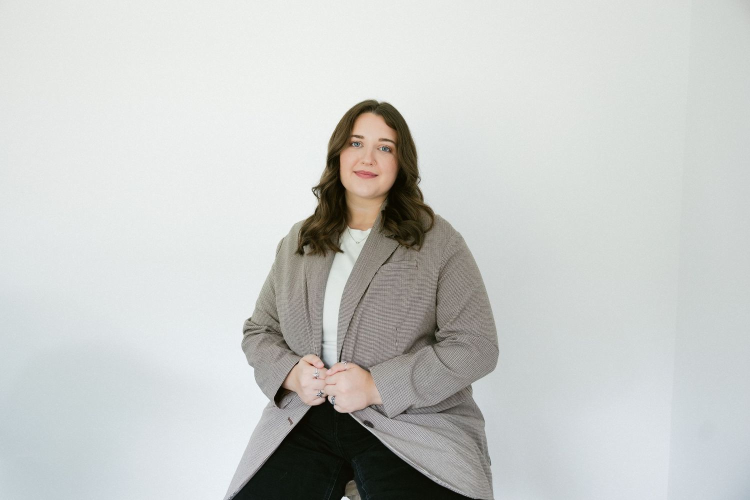 Plus size model in a gray blazer and black pants poses against a white background for professional photos.