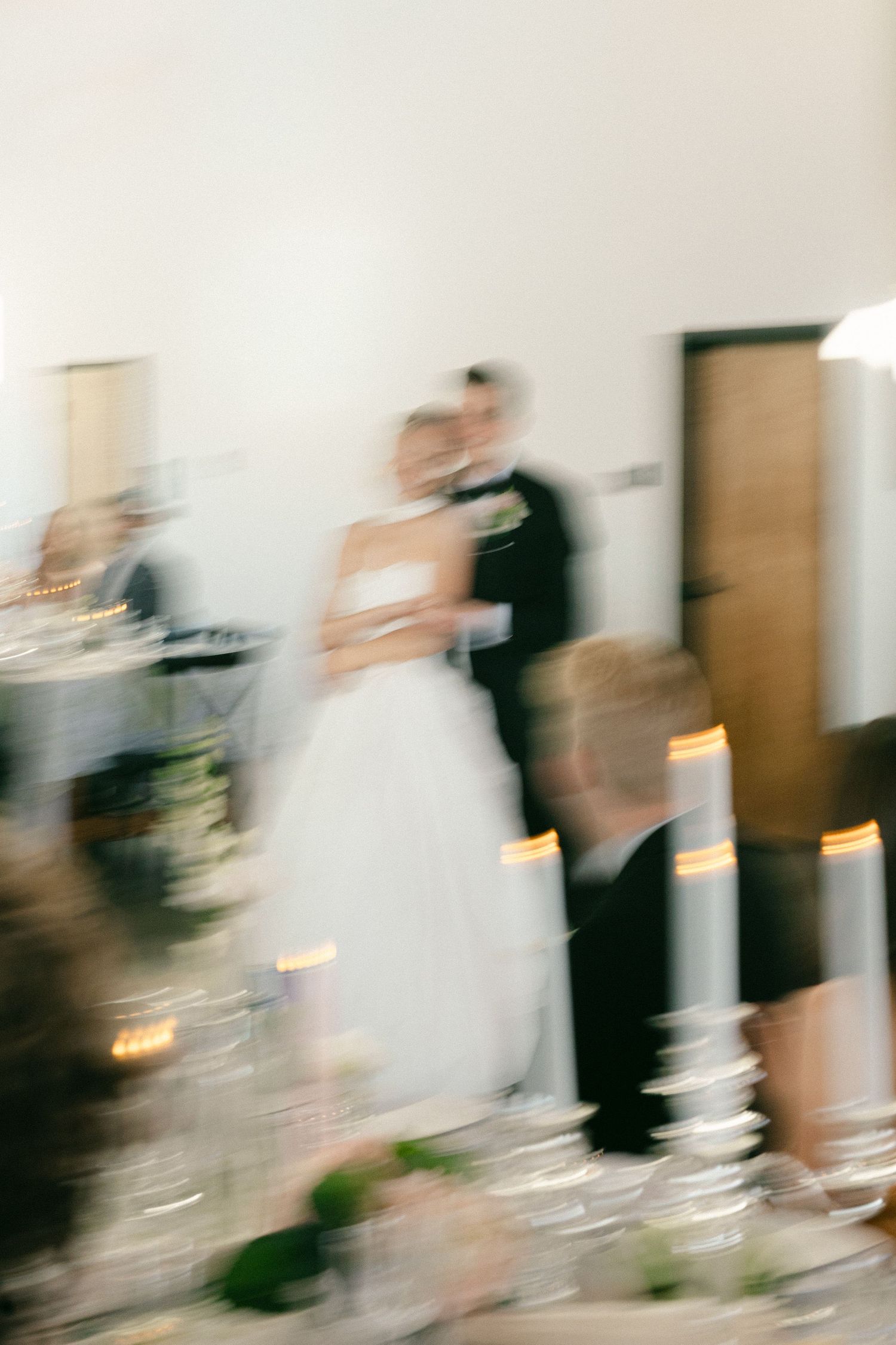 Bride and groom share a kiss at elegant candlelit wedding reception with motion blur effect.