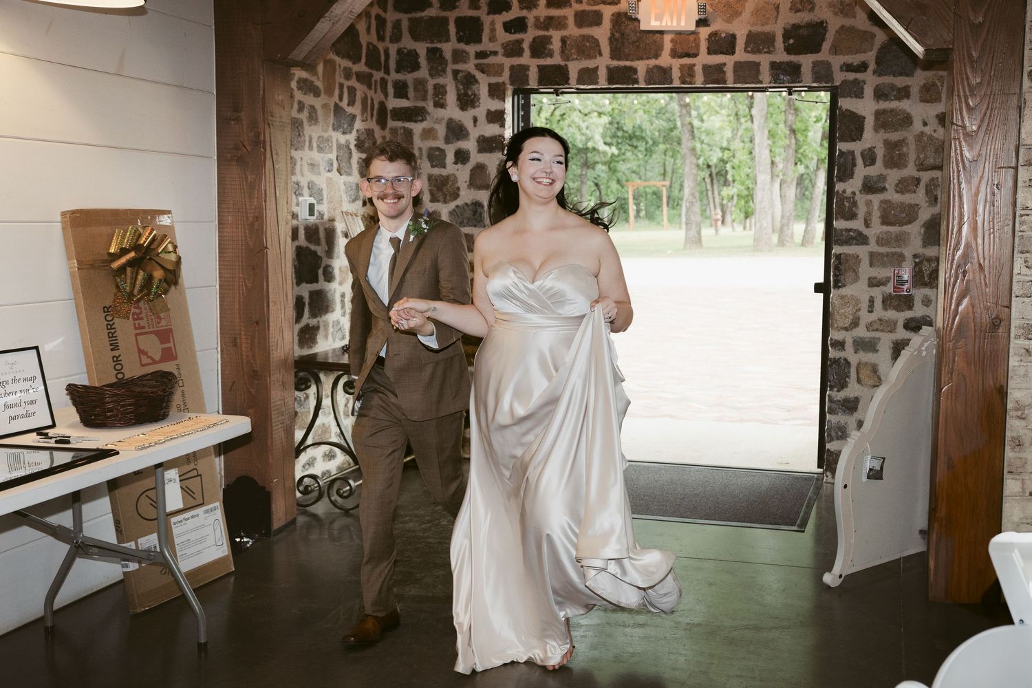 A wedding couple walking through an elegant brick venue with rustic decor.