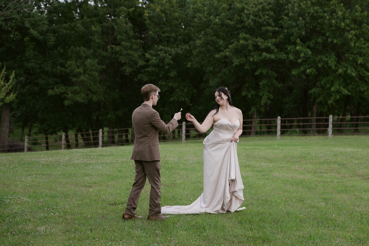 A couple shares an intimate dance moment together on a lush green lawn during their wedding celebration.