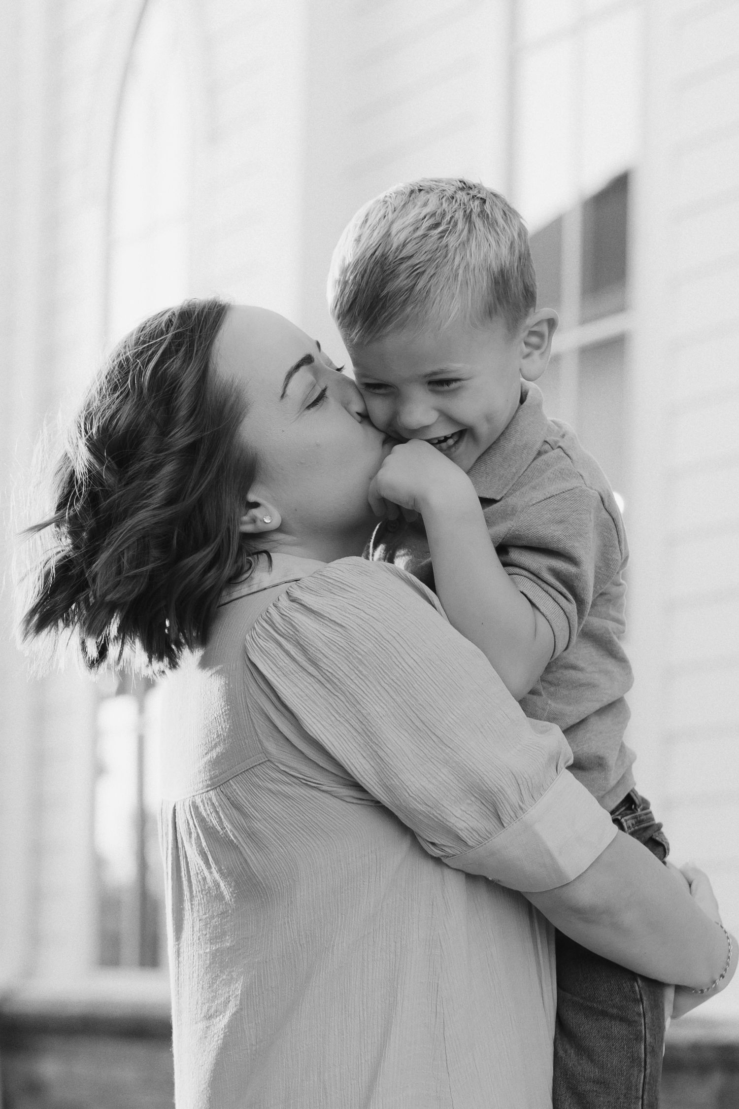 A tender black and white moment captured between a mother and child sharing laughter and affection.