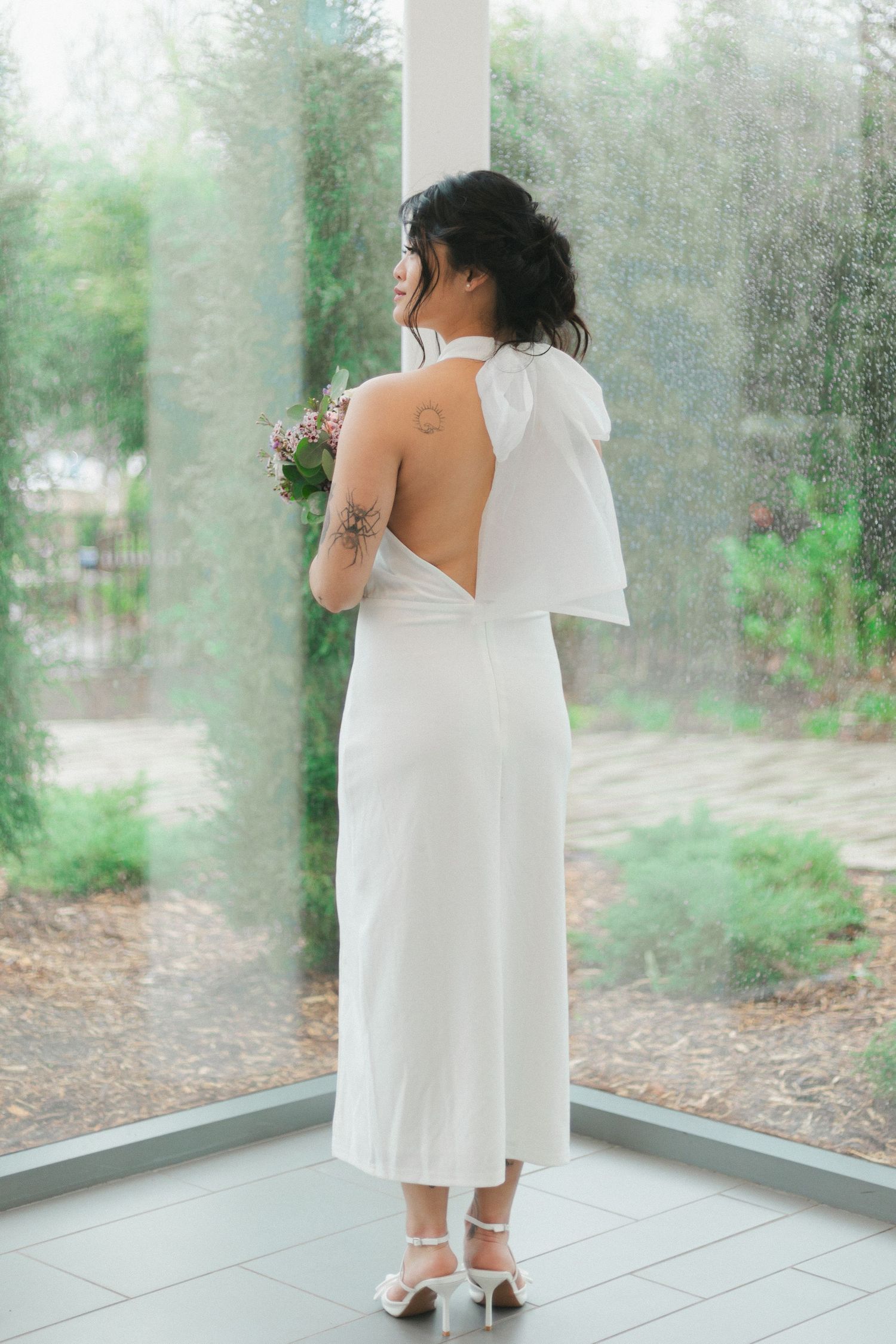 Elegant bridal portrait showing back detail of white dress and floral bouquet.