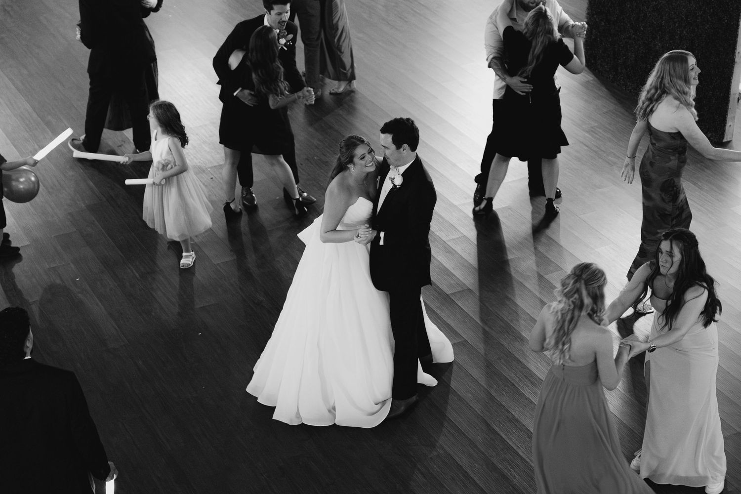 Wedding couples dancing in silhouette on a dark dance floor during a reception.