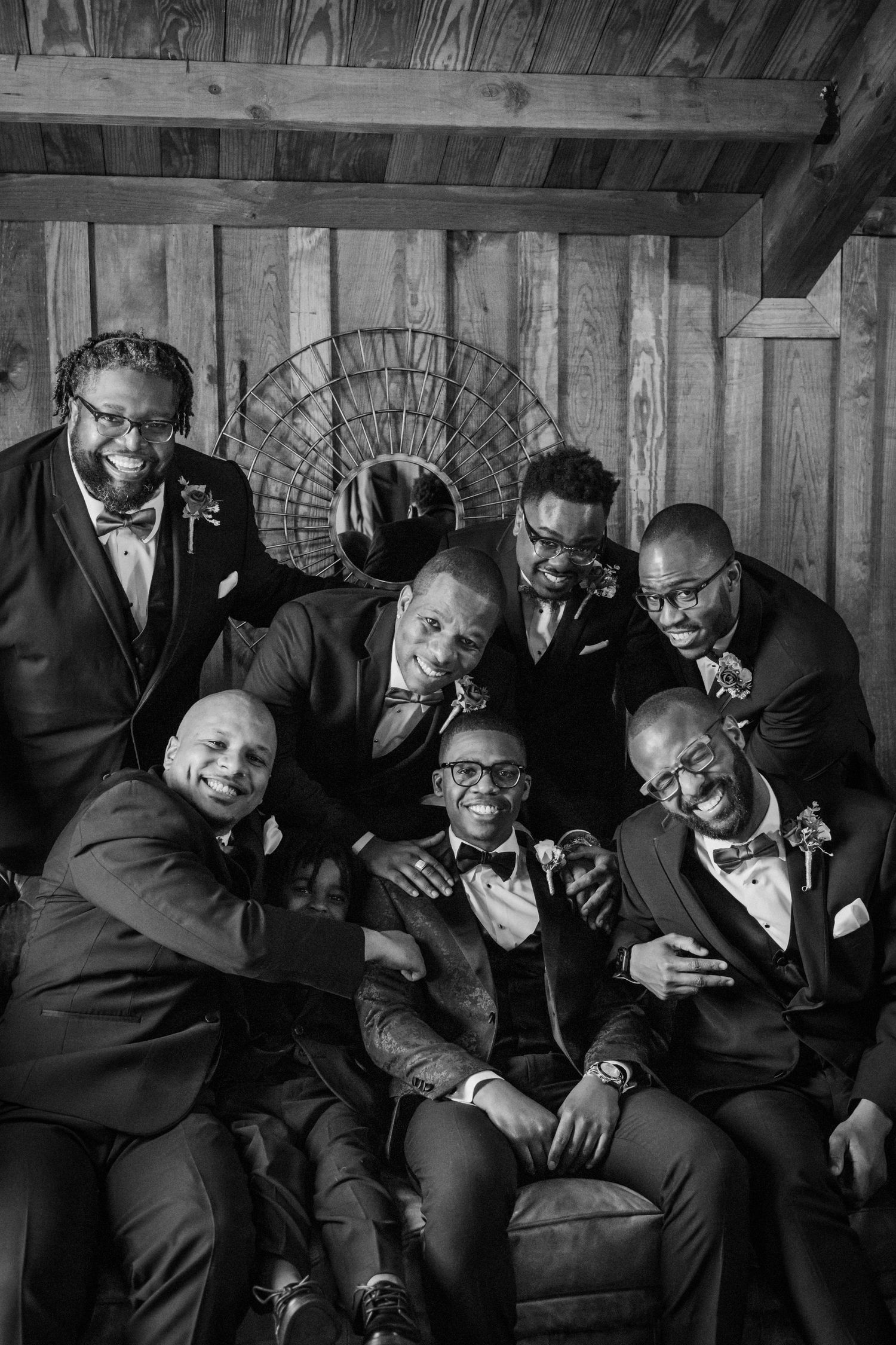 Black and white portrait of groomsmen in tuxedos posing together indoors.
