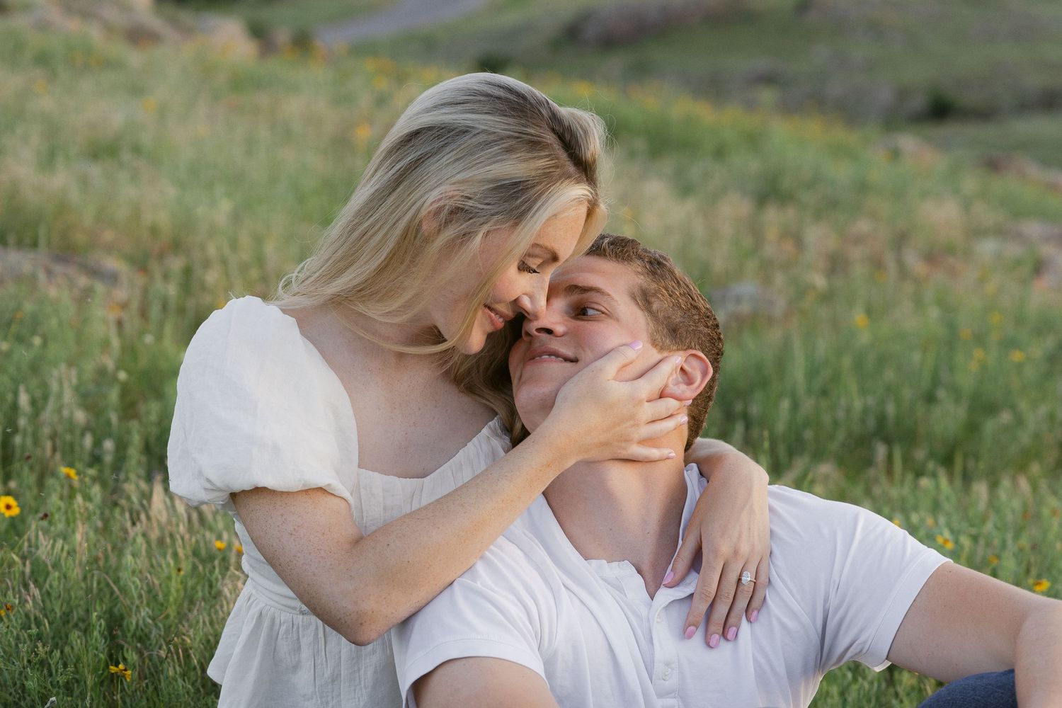 A tender moment between a couple laughing together in a wildflower field during golden hour.