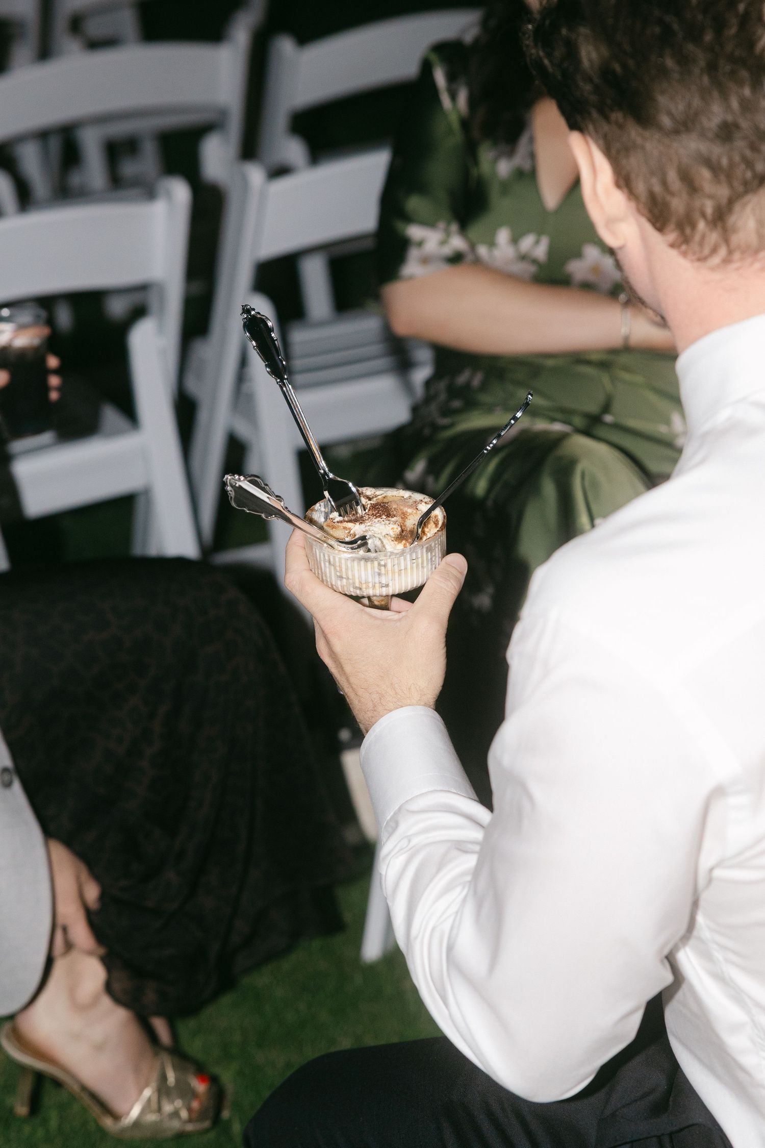 Guest holds a small silver bowl with ornate spoons at an outdoor wedding reception.