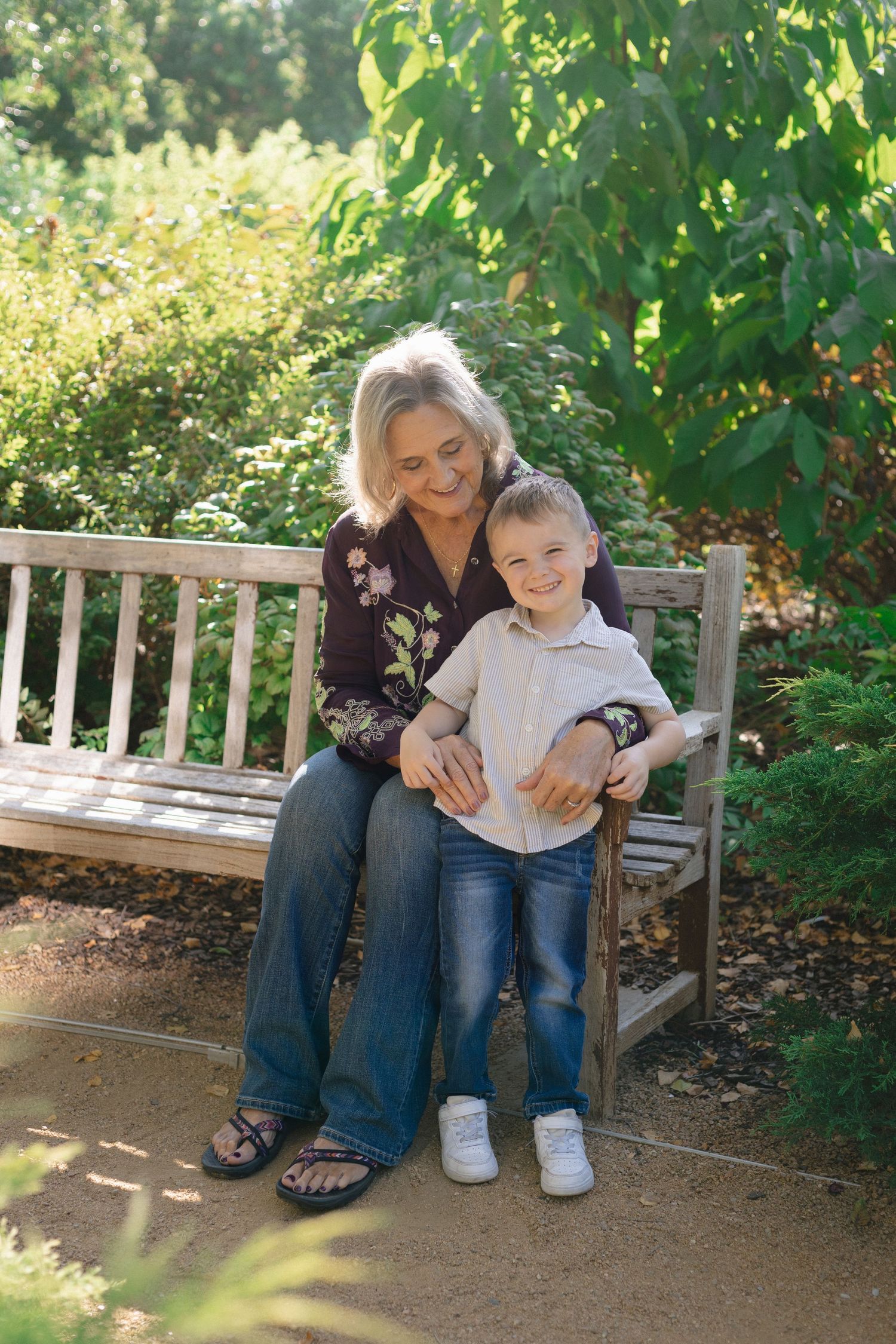 Tender moment shared on wooden garden bench surrounded by greenery.