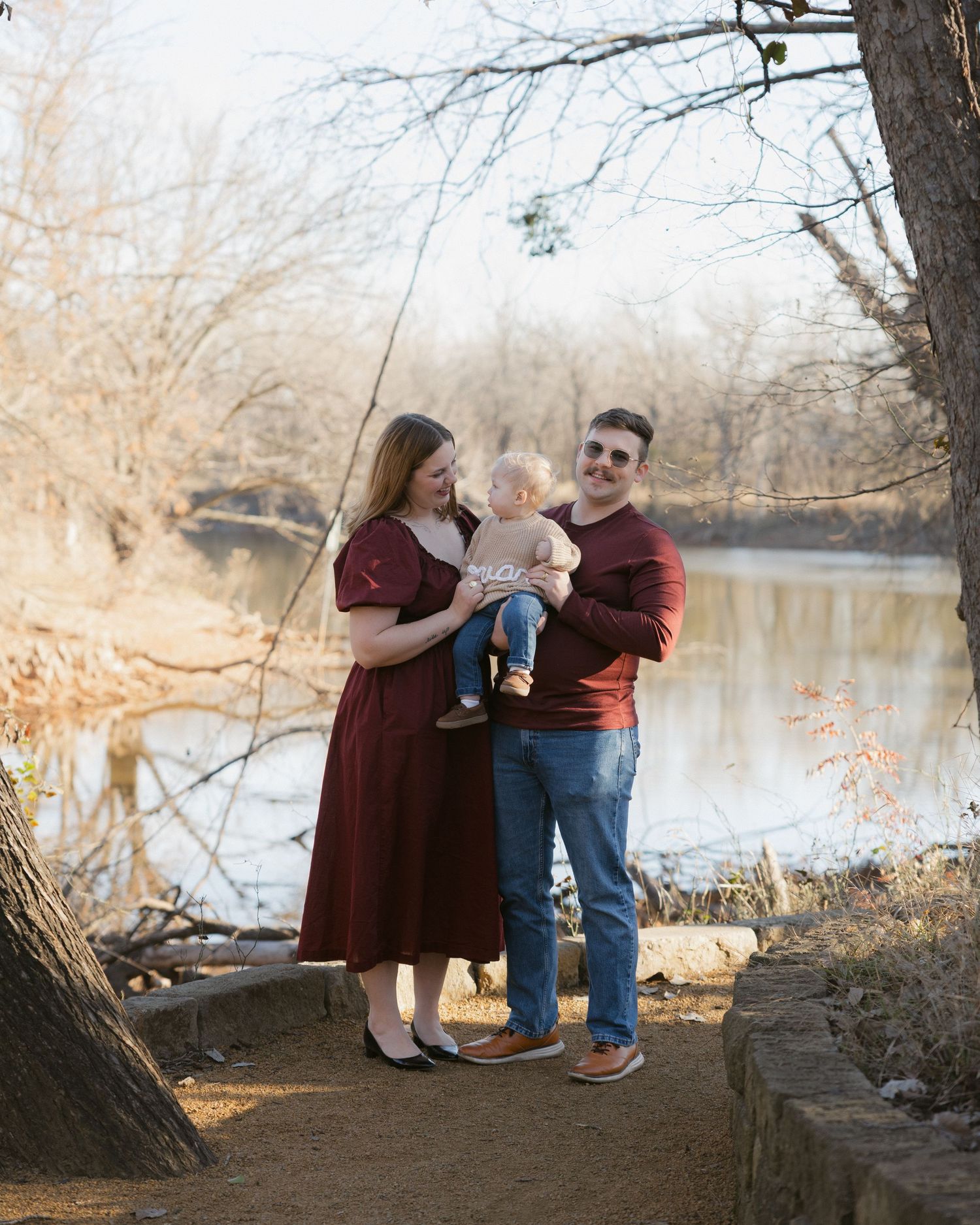 Family enjoys quality time together near a serene lake during golden hour with matching outfits.