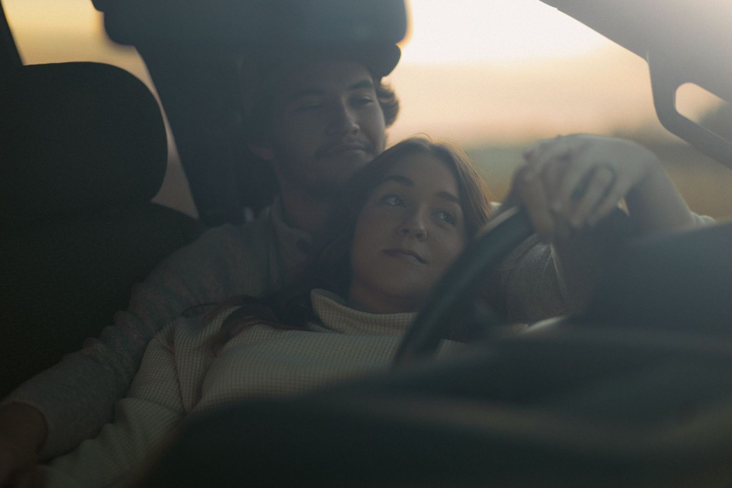 A series of dark silhouettes in car windows at sunset creating a moody atmospheric scene.