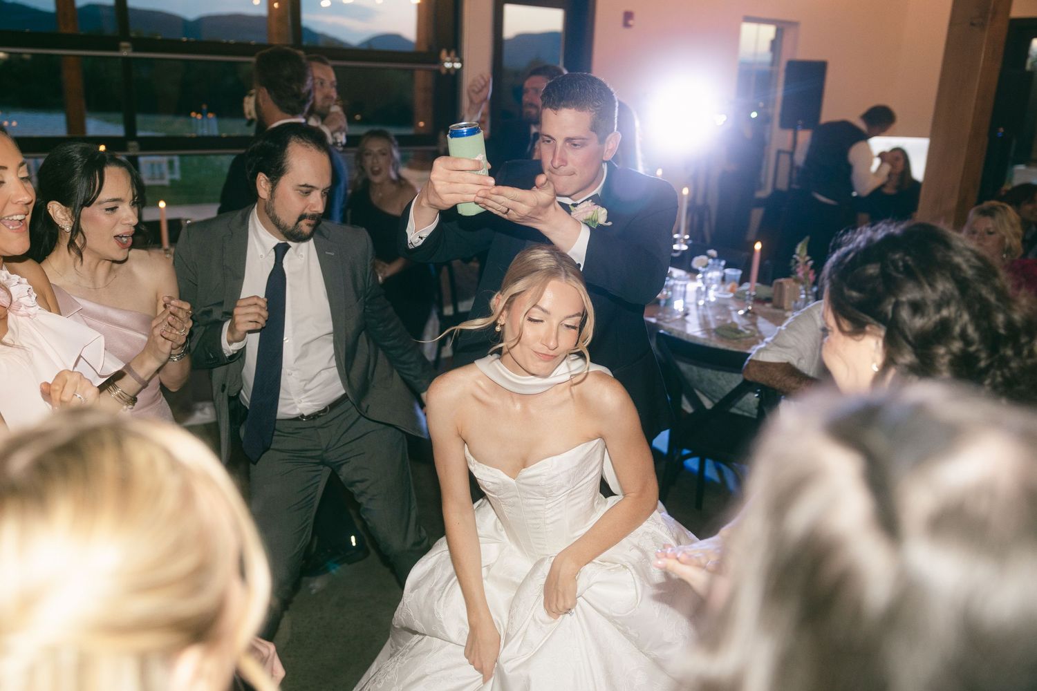 Bride and groom celebrate joyfully with guests during lively wedding reception dancing under warm lights.