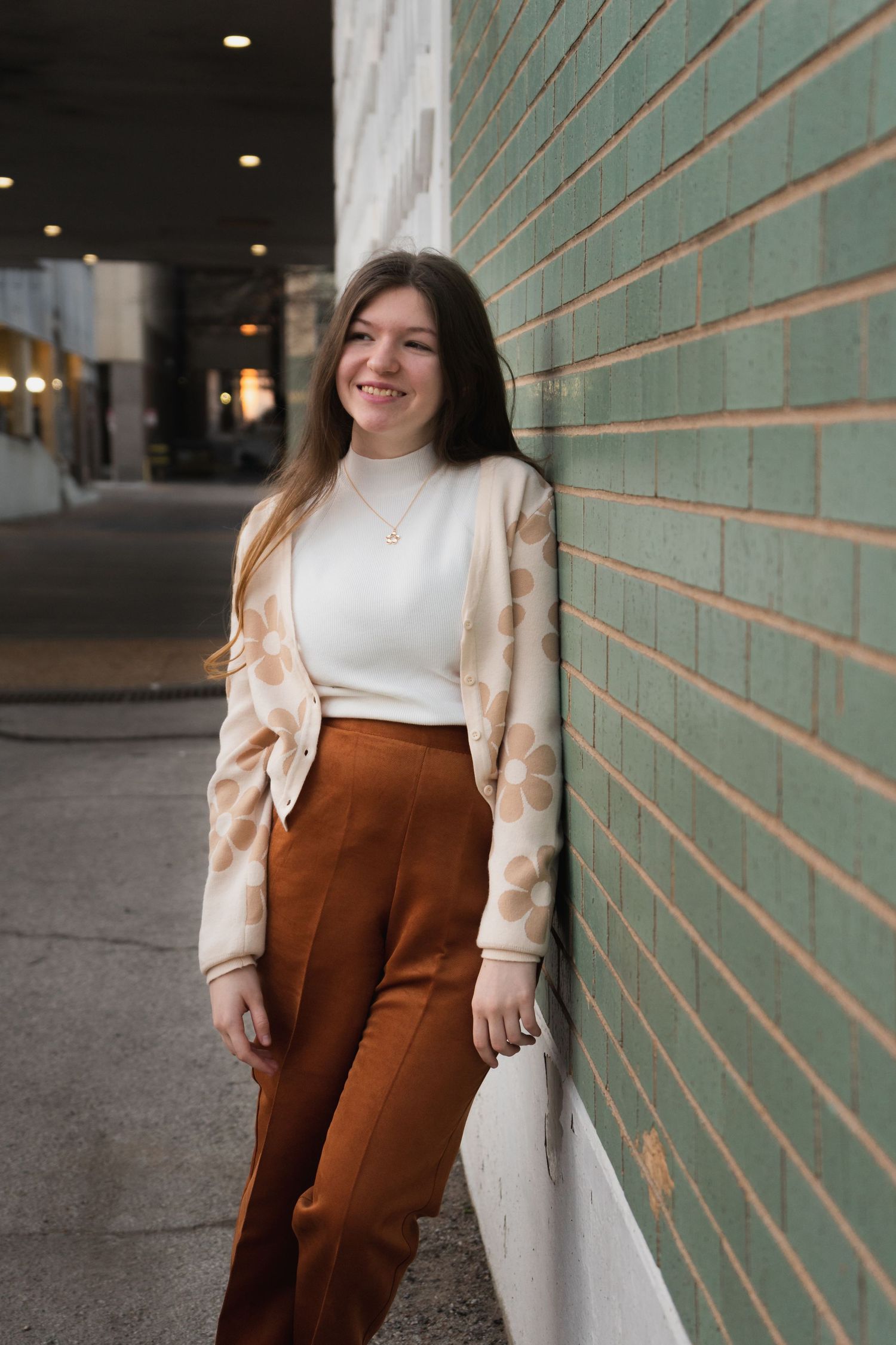 Several photos of someone wearing a cozy white sweater and brown corduroy pants against a brick wall background.