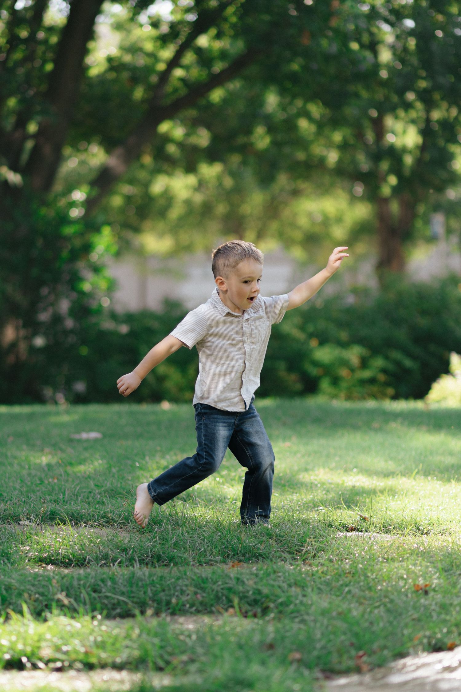 Child playing and jumping on grass in garden setting.