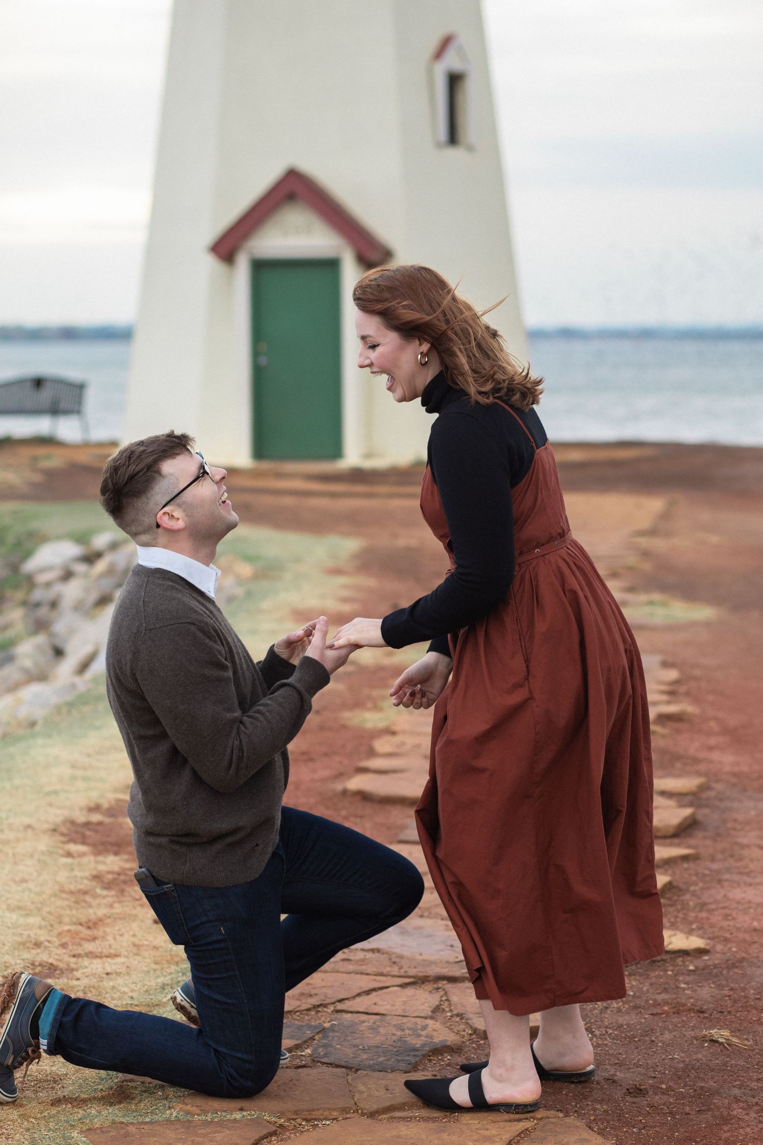 A proposal scene unfolds in a series of photos near a coastal lighthouse on red rocky terrain.