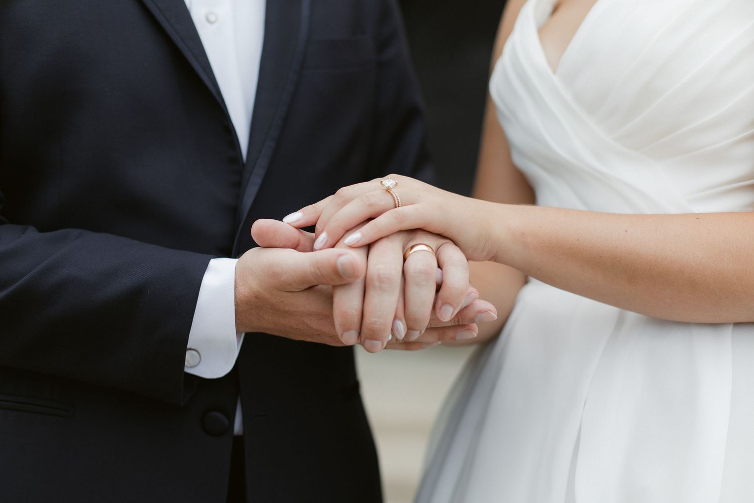 Close-up view of a bride and groom holding hands during their wedding ceremony.