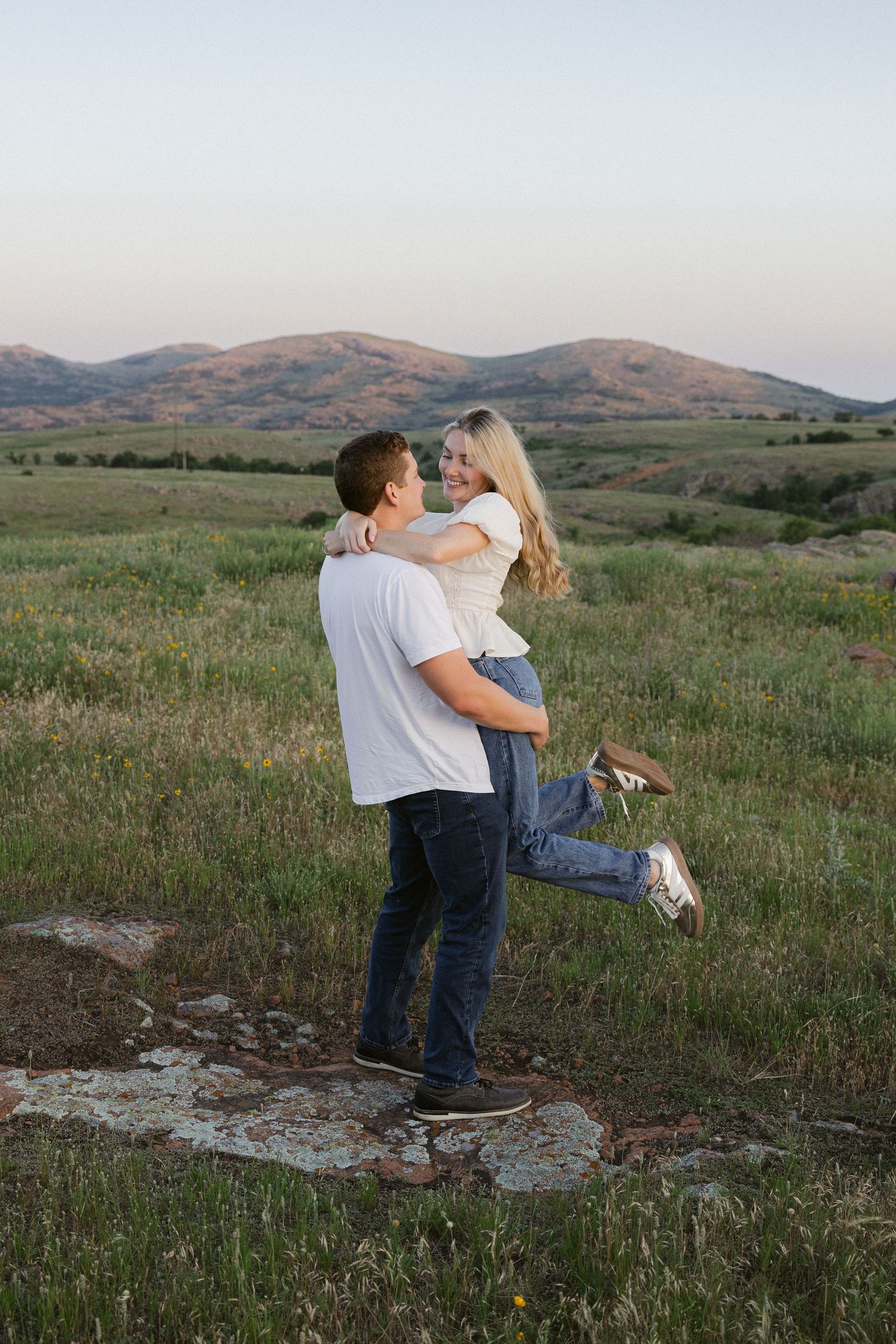 A couple dances and embraces in a scenic mountain meadow at dusk.