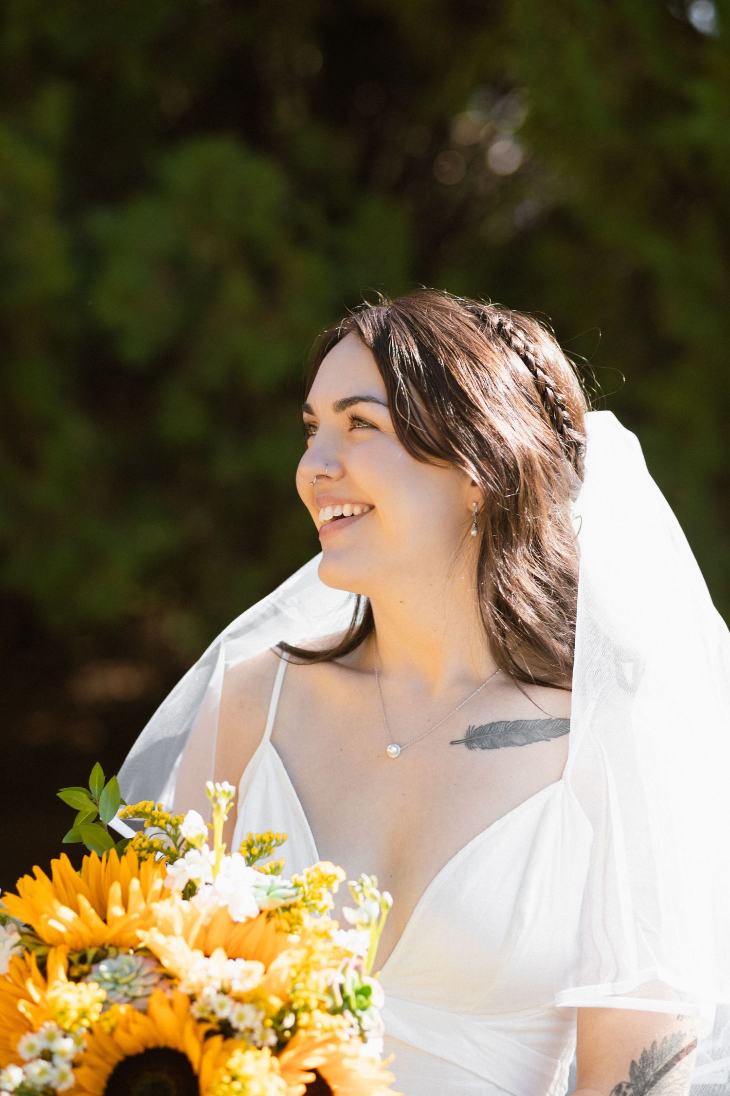 Bride with sunflowers in bouquet smiling on sunny wedding day.