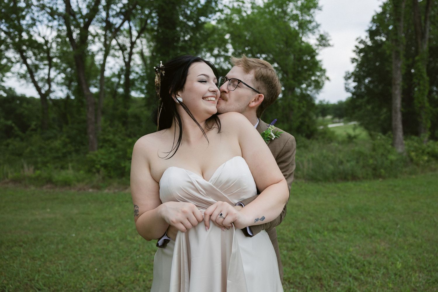 Couple shares intimate moments together in a lush green outdoor setting.