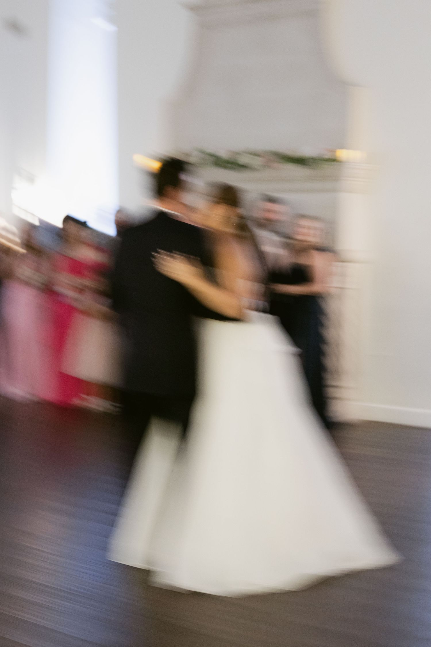 Motion-blurred image of couples dancing at a wedding reception.