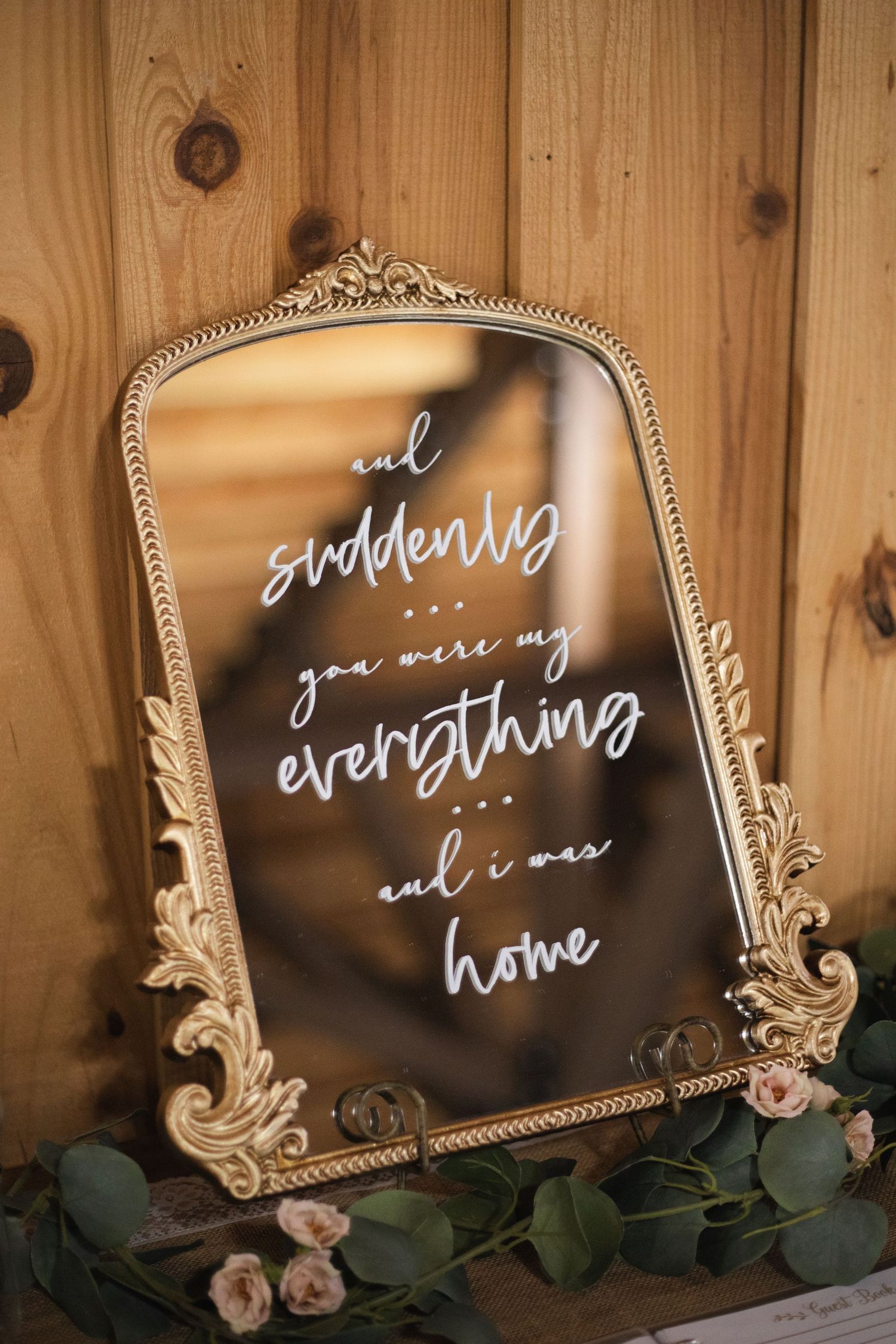 Ornate vintage-style gold frames with romantic handwritten text on dark surfaces decorated with roses and greenery.