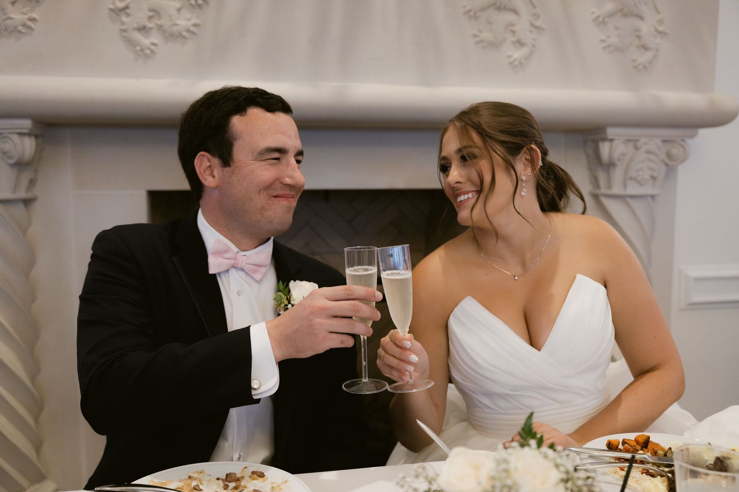 A newlywed couple shares a toast at their reception table.