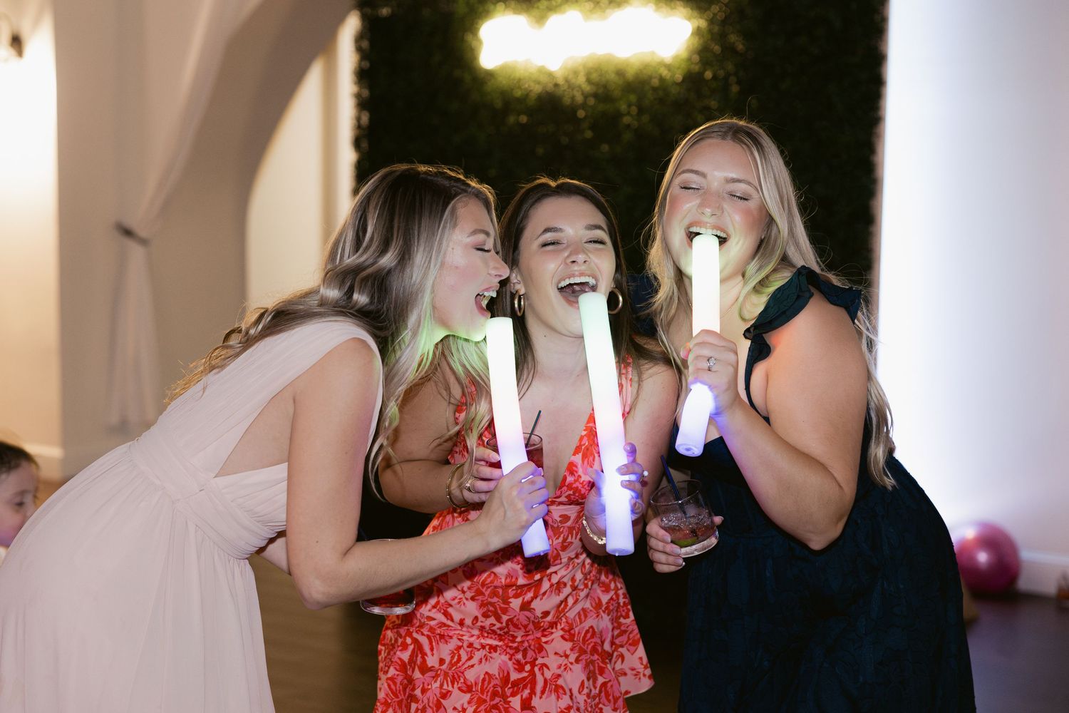 Wedding party guests celebrating and dancing with glowing light-up accessories at a reception.