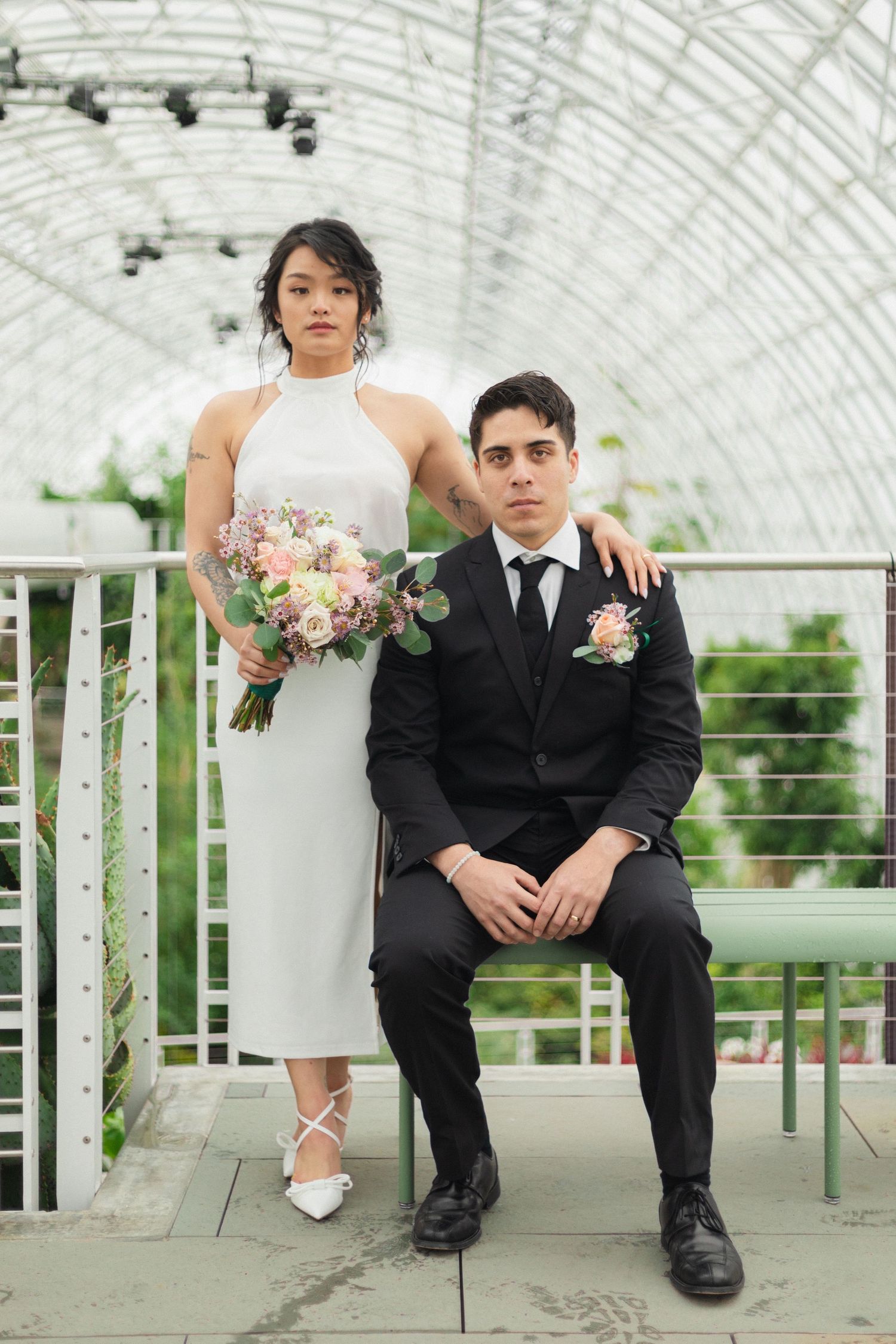 Modern wedding portrait in a greenhouse with architectural details and natural lighting.